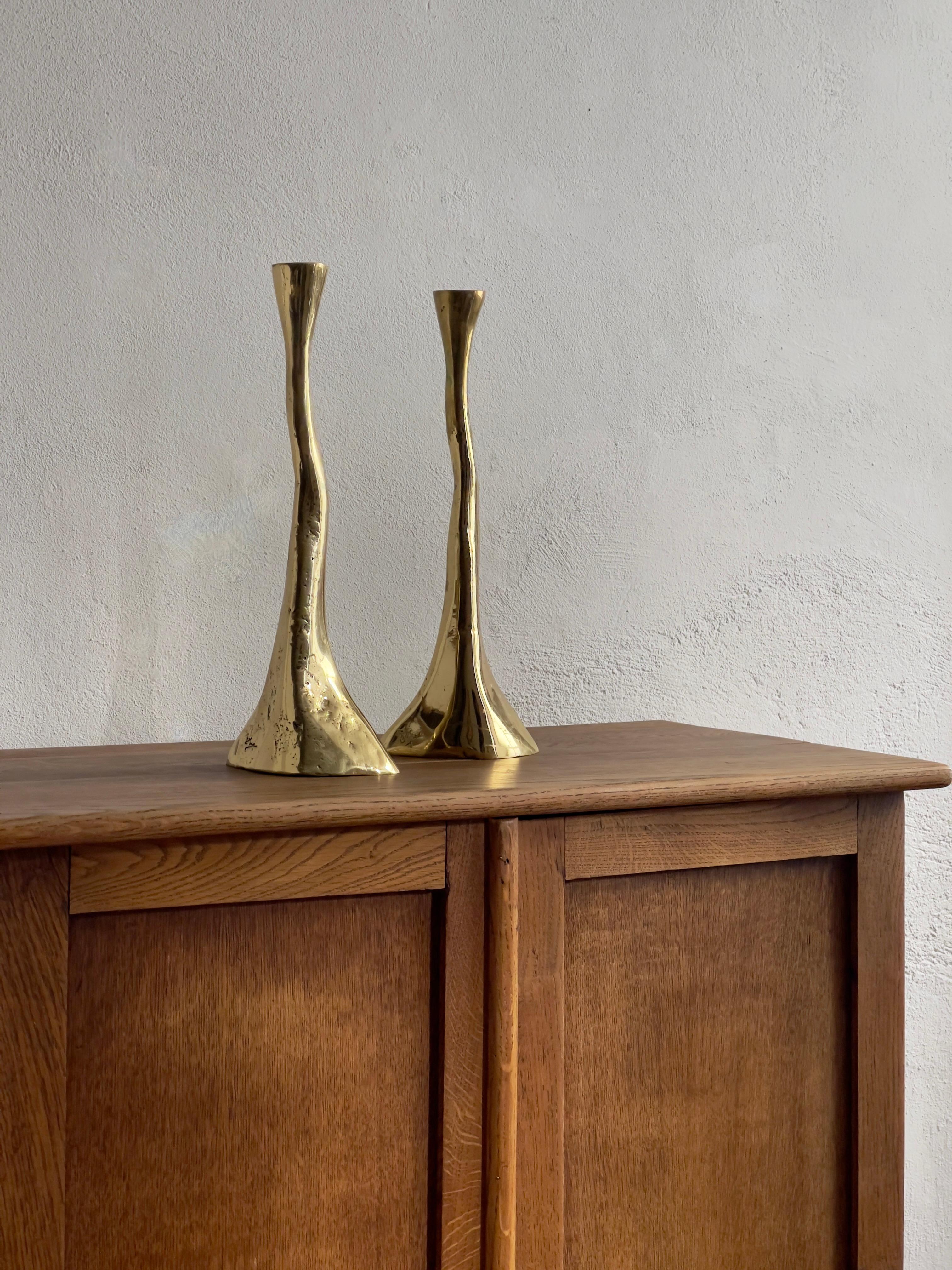 A rare pair of solid and heavy brass candlesticks from mid-20th century Denmark is a captivating testament to the fusion of craftsmanship and design inherent in the era's decorative arts.

The rustic  casting technique employed in their creation