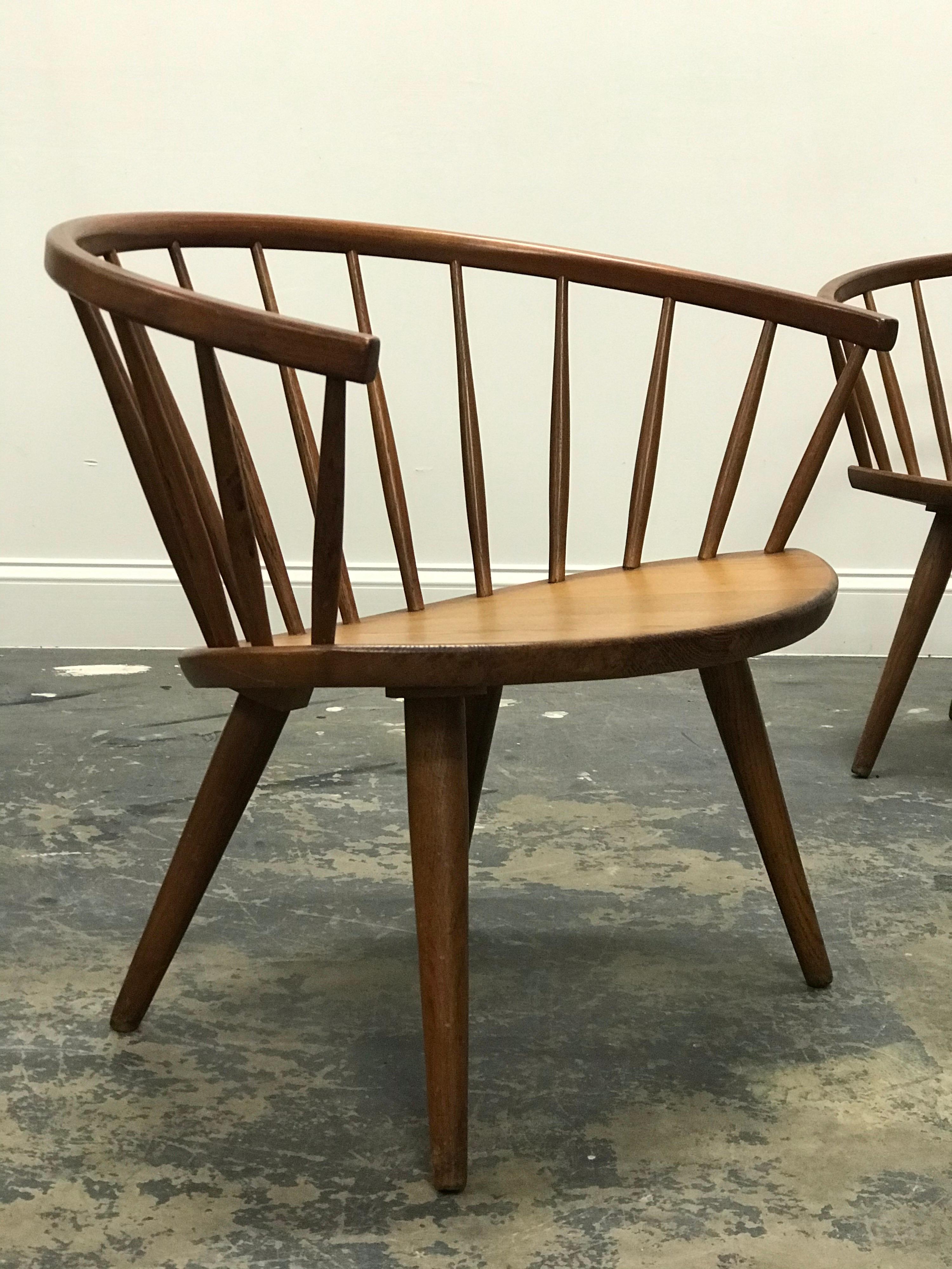 Uncommon pair of chairs designed by Yngve Ekström. Chairs feature solid oak construction and spindled backs. Chairs have worn exceptionally well over the years and the natural patina shows beautifully.