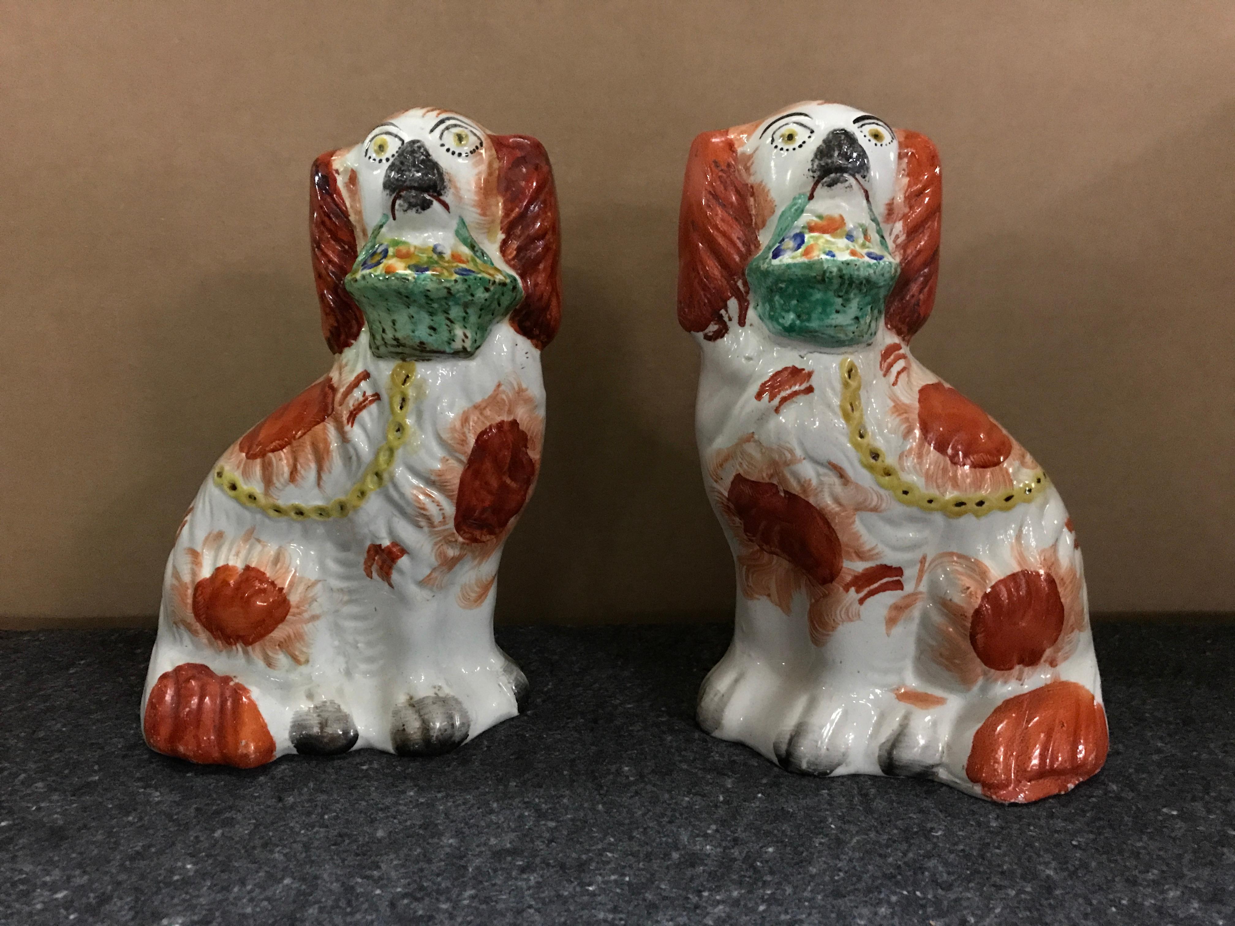 Rare pair of Staffordshire seated red spaniels with baskets of flowers, each one well painted with expressive faces and colorful floral baskets.

 