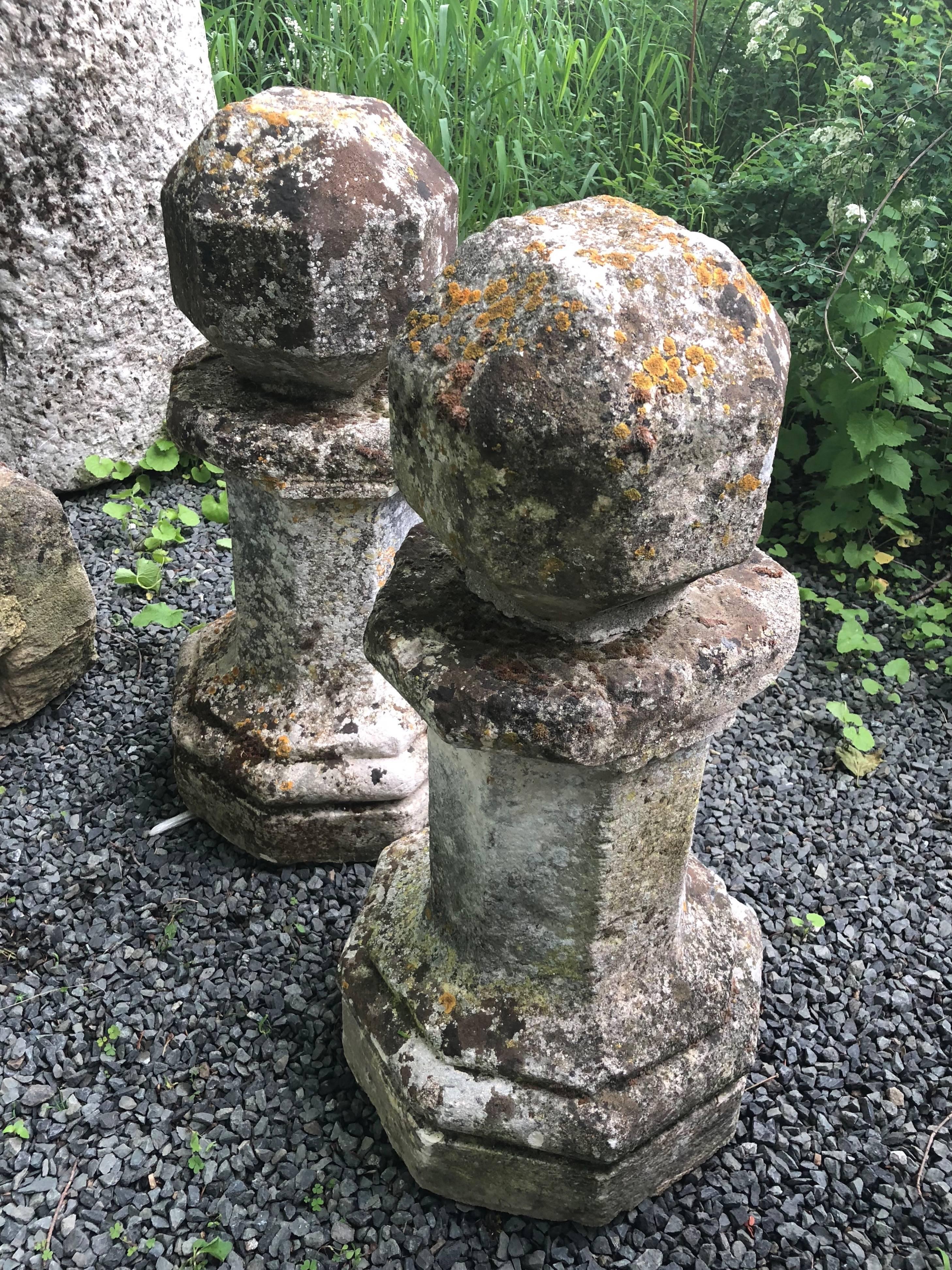 This rare and very special pair of early hand-carved limestone finials features stepped octagonal bases, tall octagonal risers, octagonal collars, and polyhedron balls at the top. Each has a flattened back section to the collars (so two out of eight