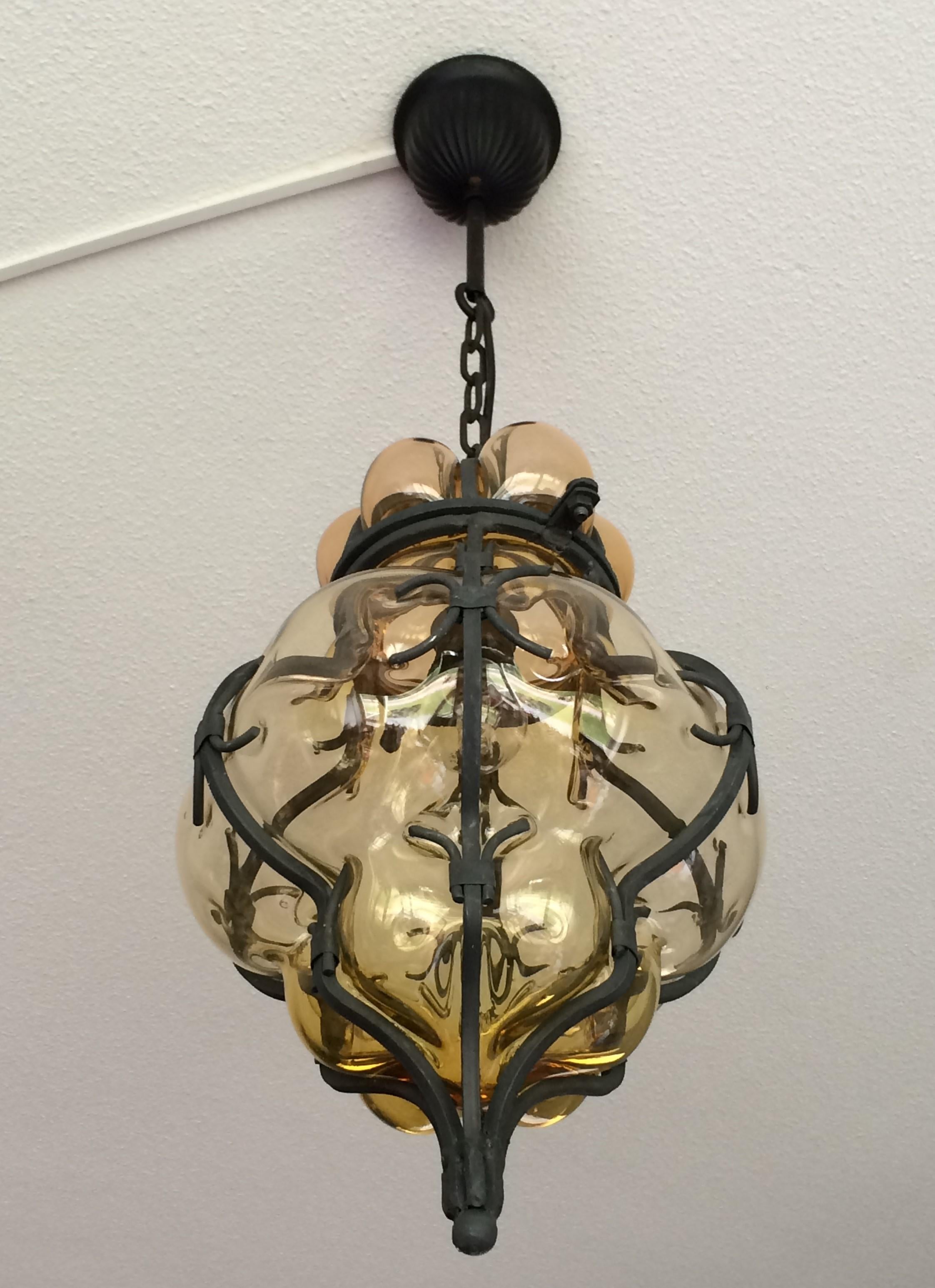 These handcrafted and stylish pendants are in near-mint condition.

This pair of single light, Italian pendants is very beautiful, both in shape and in color. The stunning amber glass is mouth-blown into hand forged, wrought iron frames and the