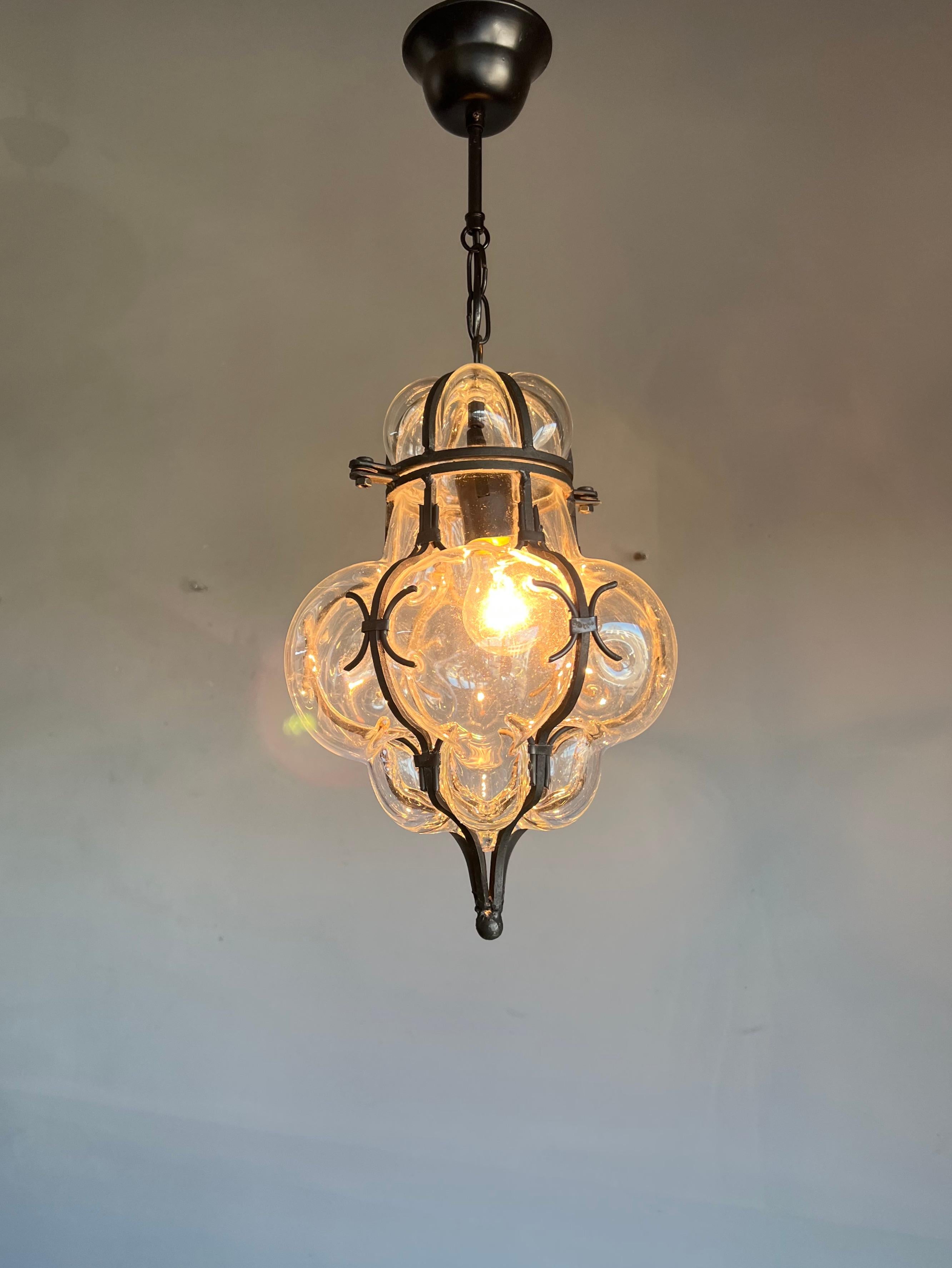 These handcrafted and stylish pendants are in near-mint condition.

This pair of single light, Italian pendants is very beautiful, both in shape and in color. The stunning clear glass is mouth-blown into hand forged, wrought iron frames and the