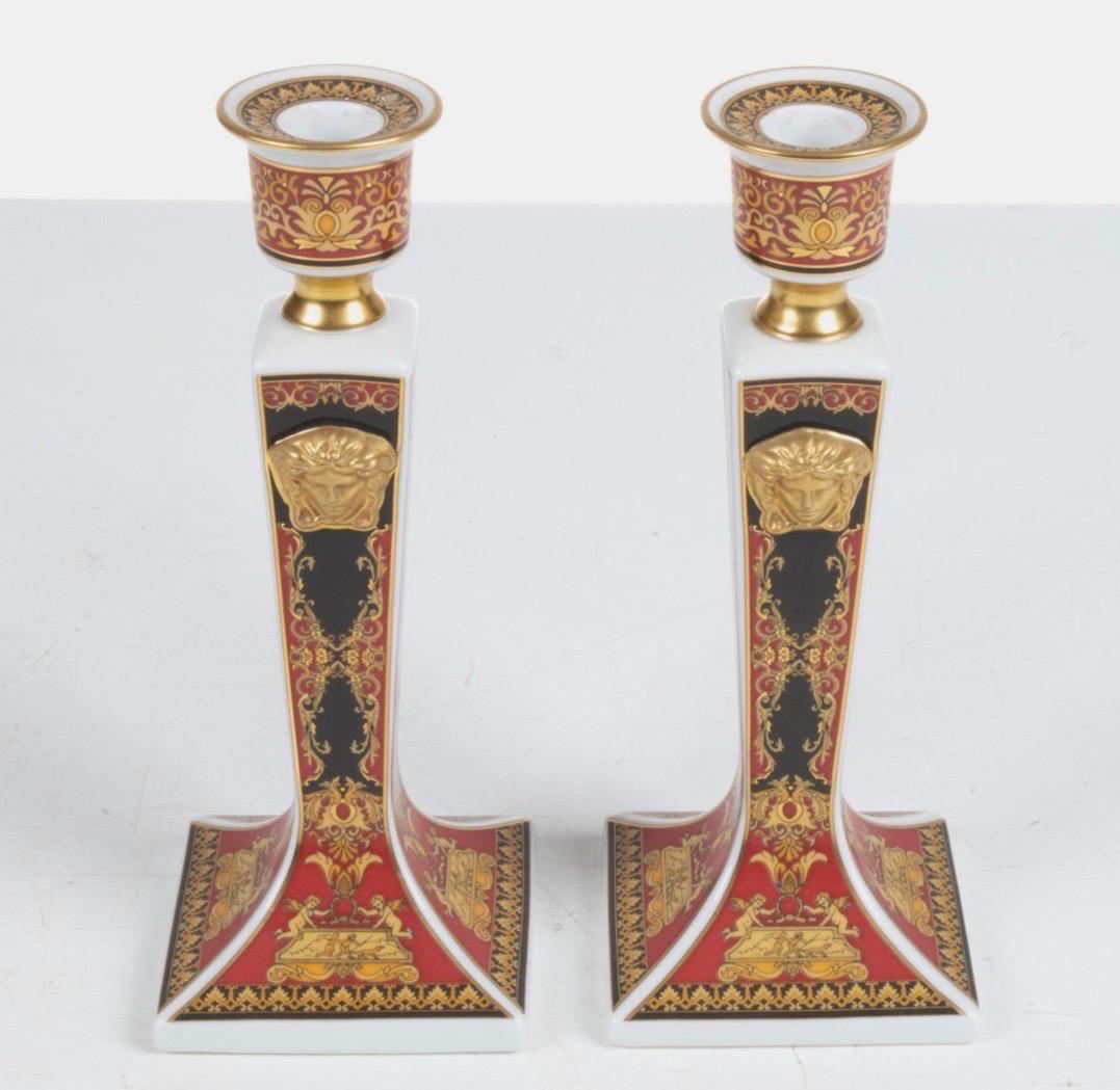 Pair of stunning porcelain candlesticks designed by Versace and made by Rosenthal - in the coveted Medusa style.  These highly decorative candlesticks are of red and black design with gold gilt embossed pattern on a porcelain white body.  Versace