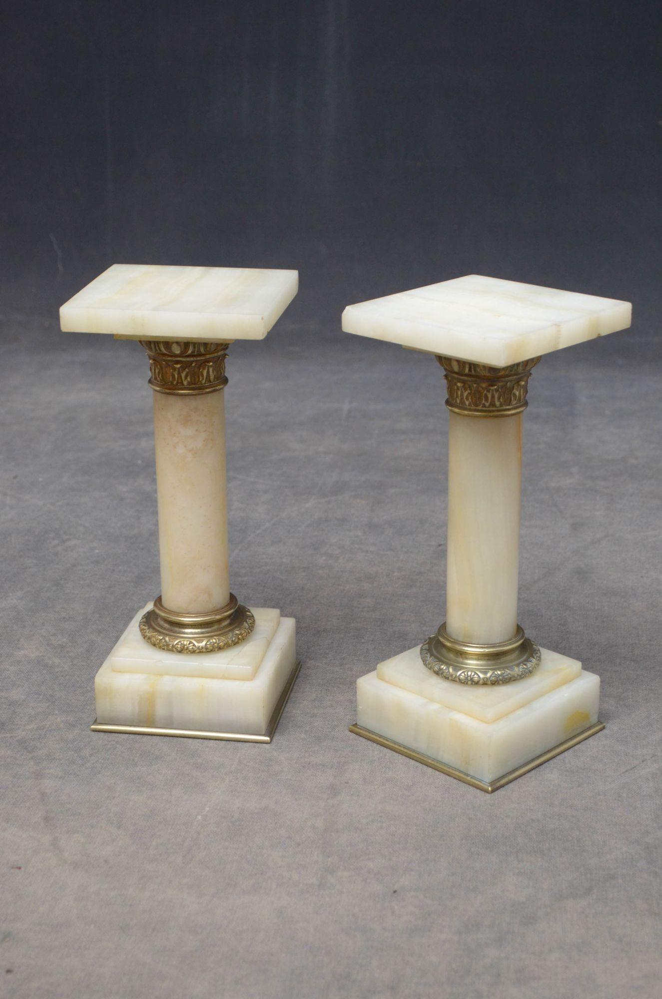 K081, a rare pair of antique marble columns in white veined marble, each having a square platform top (one with small chip to the corner), brass collar, veined columns terminating in brass collar and stepped veined base, standing on brass moulding.