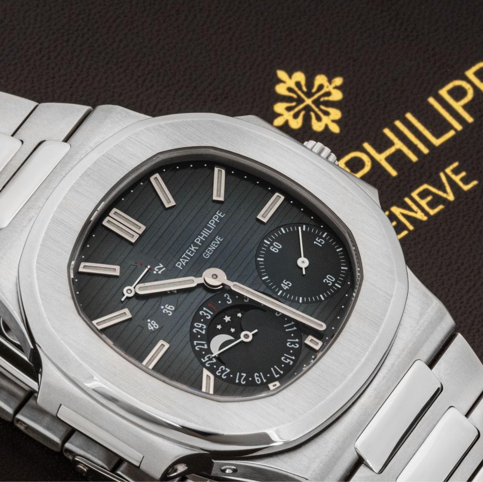 Eine sehr seltene Edelstahl-Nautilus-Armbanduhr von Patek Philippe. Sie verfügt über ein schwarz-graues Zifferblatt mit applizierten Stundenmarkierungen, kleiner Sekunde, Datums- und Mondphasenanzeige sowie einer Gangreserveanzeige.

Ausgestattet