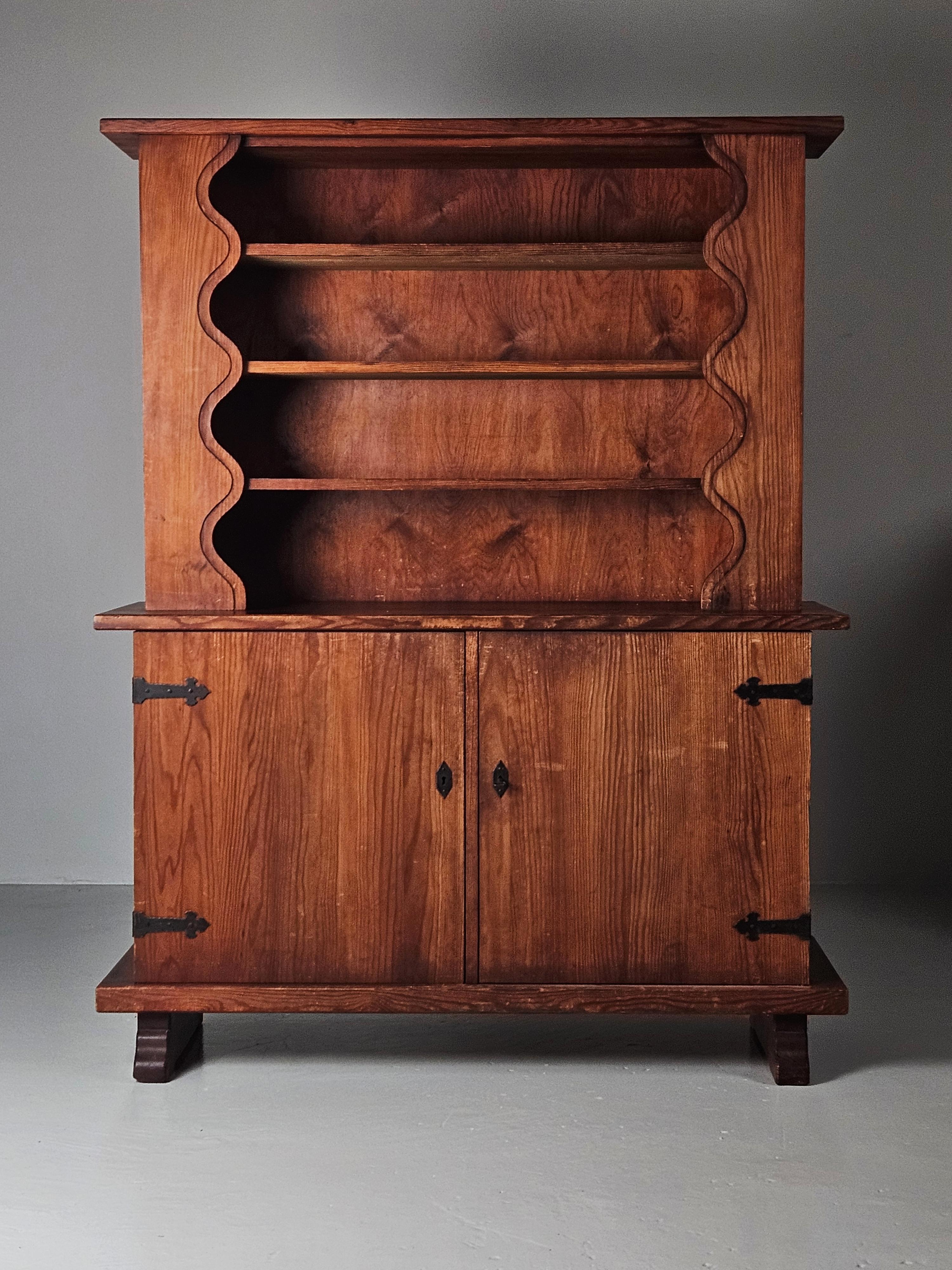 Very rare cabinet produced in Sweden, 1940s. 

Made in solid pine with elements of iron. 

The wavy form of the top shelf as well as the legs of the cabinet makes you think of Axel Einar Hjorts sports cabin furniture produced by Nordiska Kompaniet