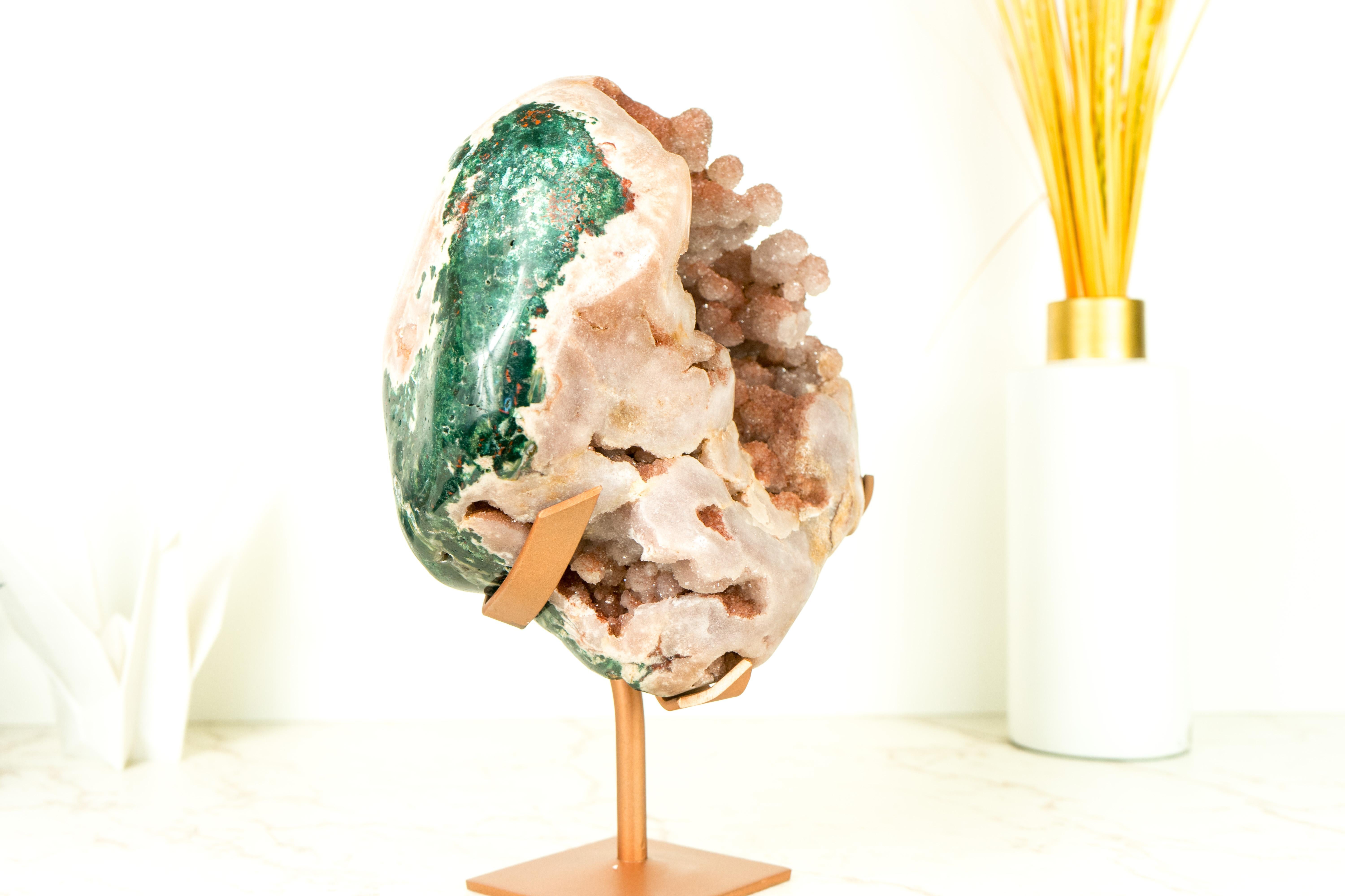 Presentando una rara forma di ametista rosa, questo geode è un pezzo unico di arte naturale caratterizzato da lucidi drughi di zucchero in cima a formazioni botrioidali che si sono sviluppate nel corso di milioni di anni. Questa rara ametista rosa