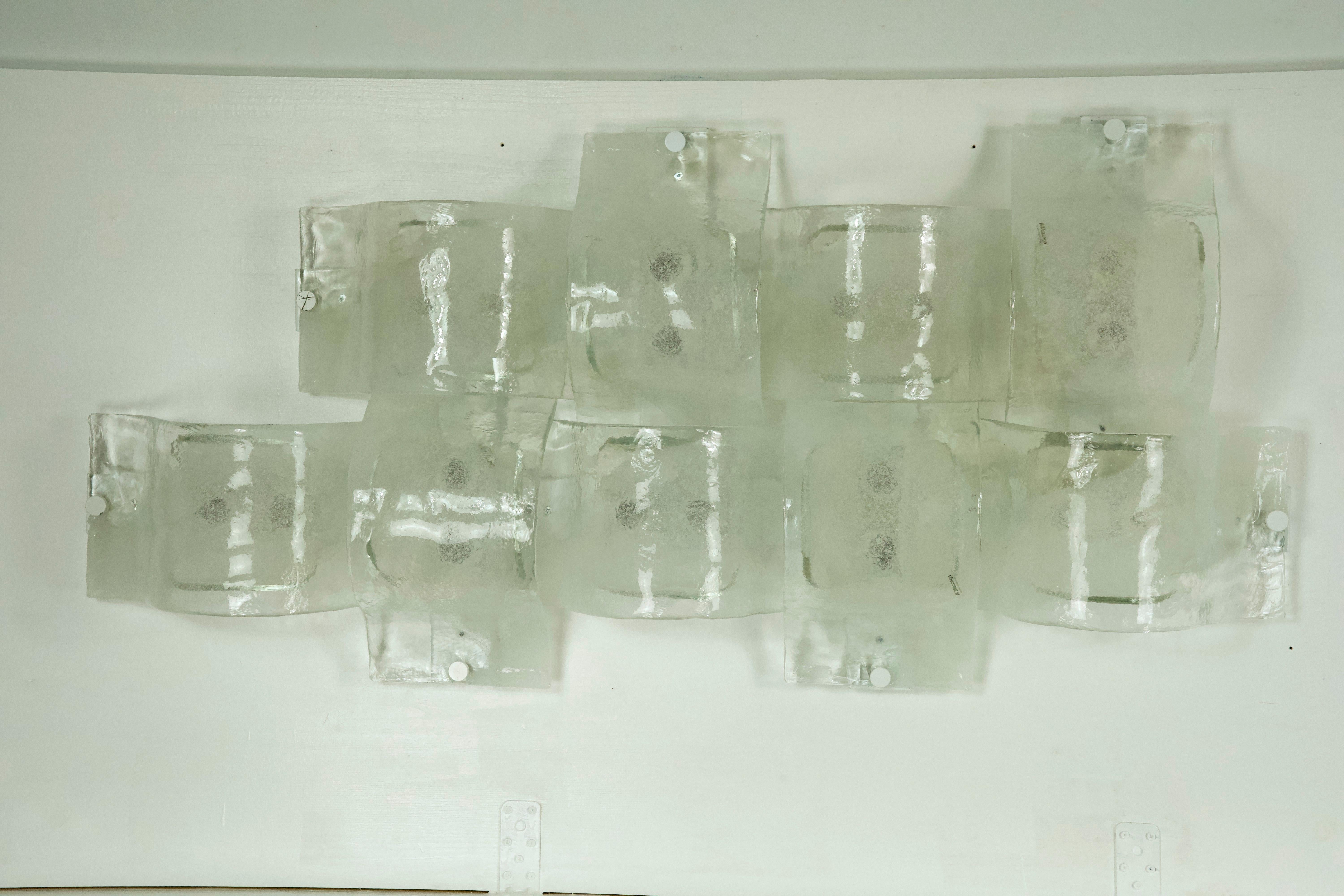 Composed of 9 Murano glass wall lamps produced by Mazzega in the 1970s. They can be installed as a panel or separately as 9 individual sconces. Full working with EU standard, adaptable on demand for USA standard.
