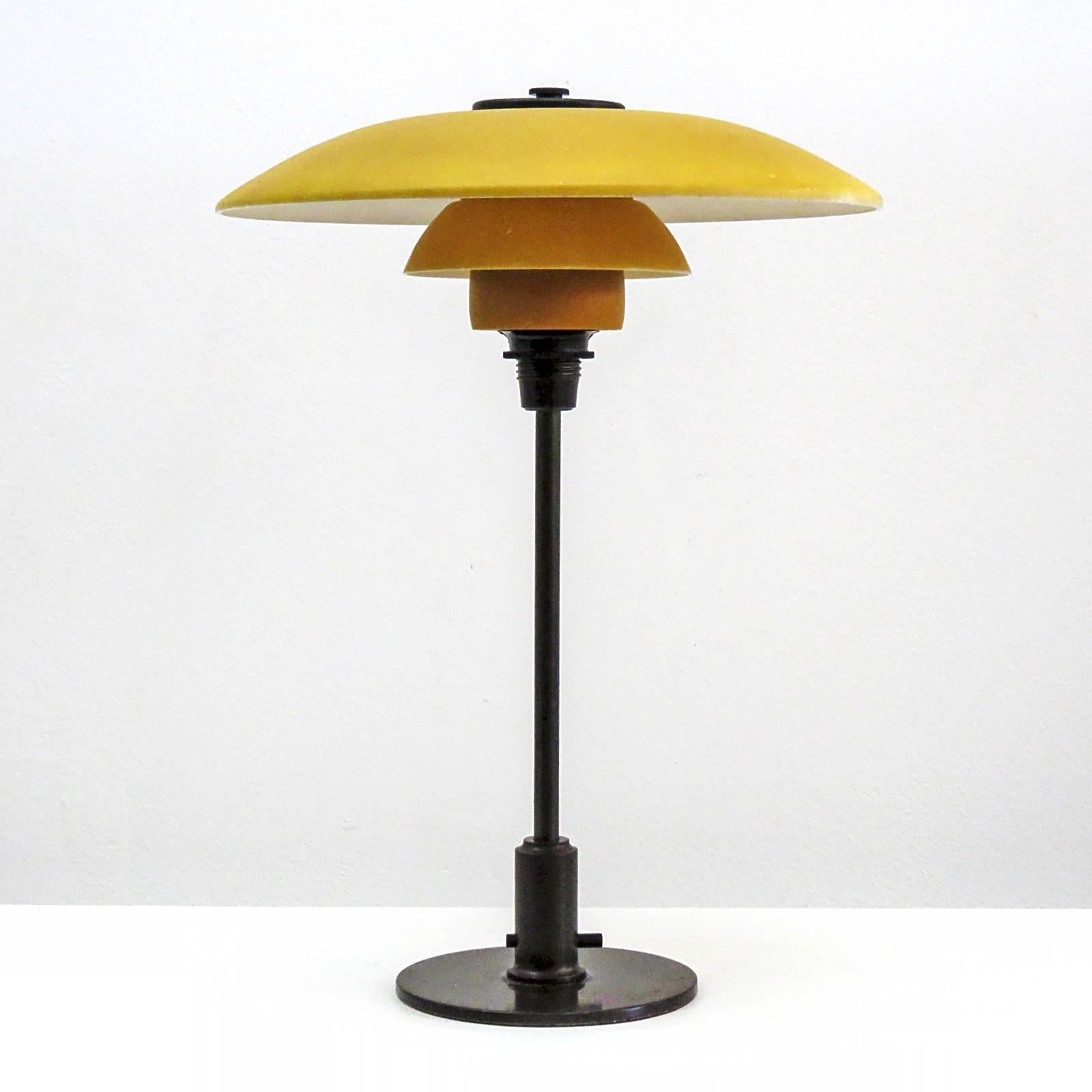 Rare Poul Henningsen. PH-3½/2 table lamp with original single-layer yellow painted/opal glass shade set on a browned brass stem and shade holder with wire legs. Bakelite through switch on the stem and bakelite cover plate, produced by Louis Poulsen