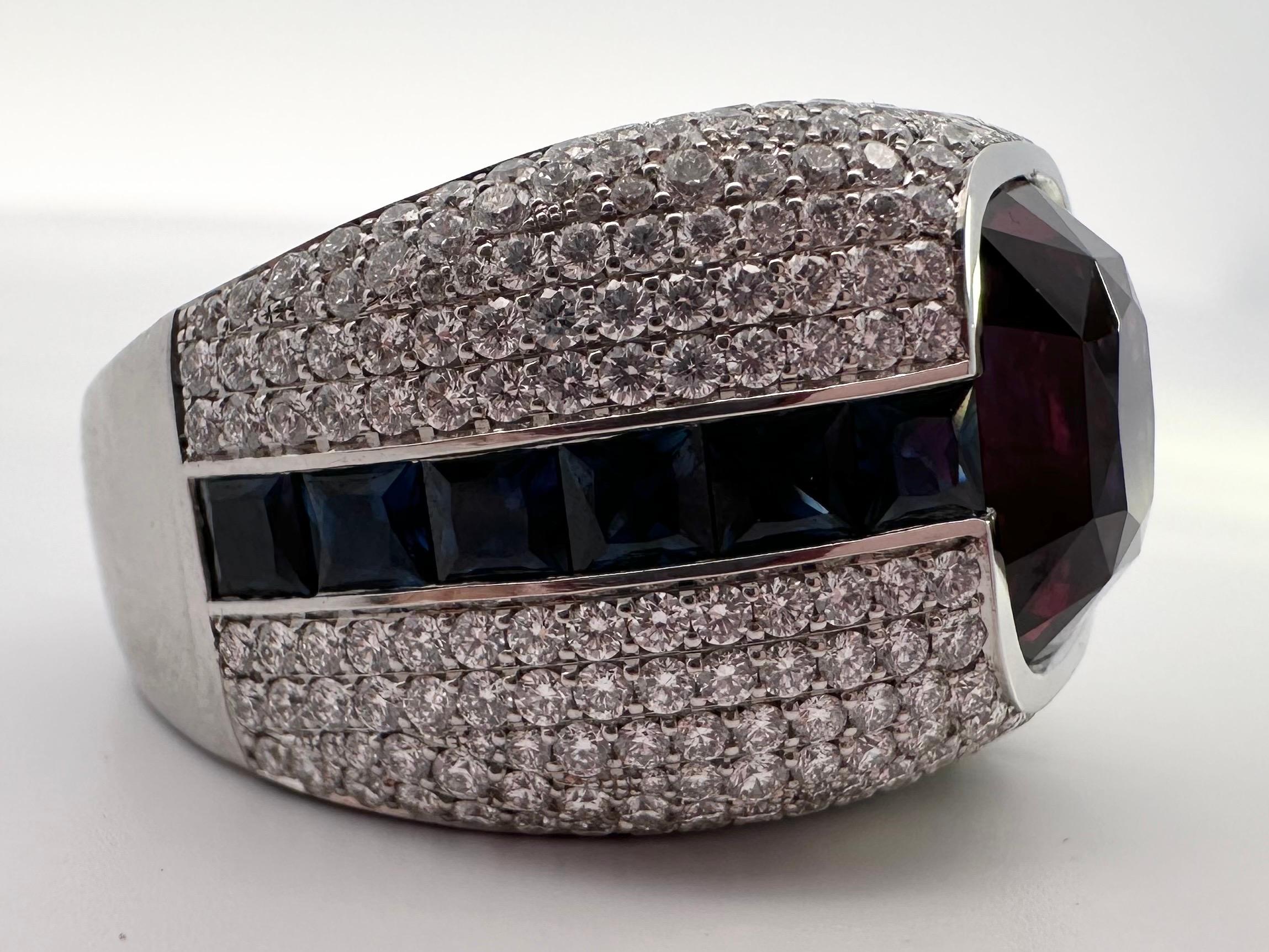 A unique purple garnet ring accompanied by sapphires and diamonds. This center is a very rare purple garnet weighing 10.58 carats, the ring comes with a certificate. Diamonds weigh 2.76 carats and are VS-SI clarity and F color. The sapphire are 3.81