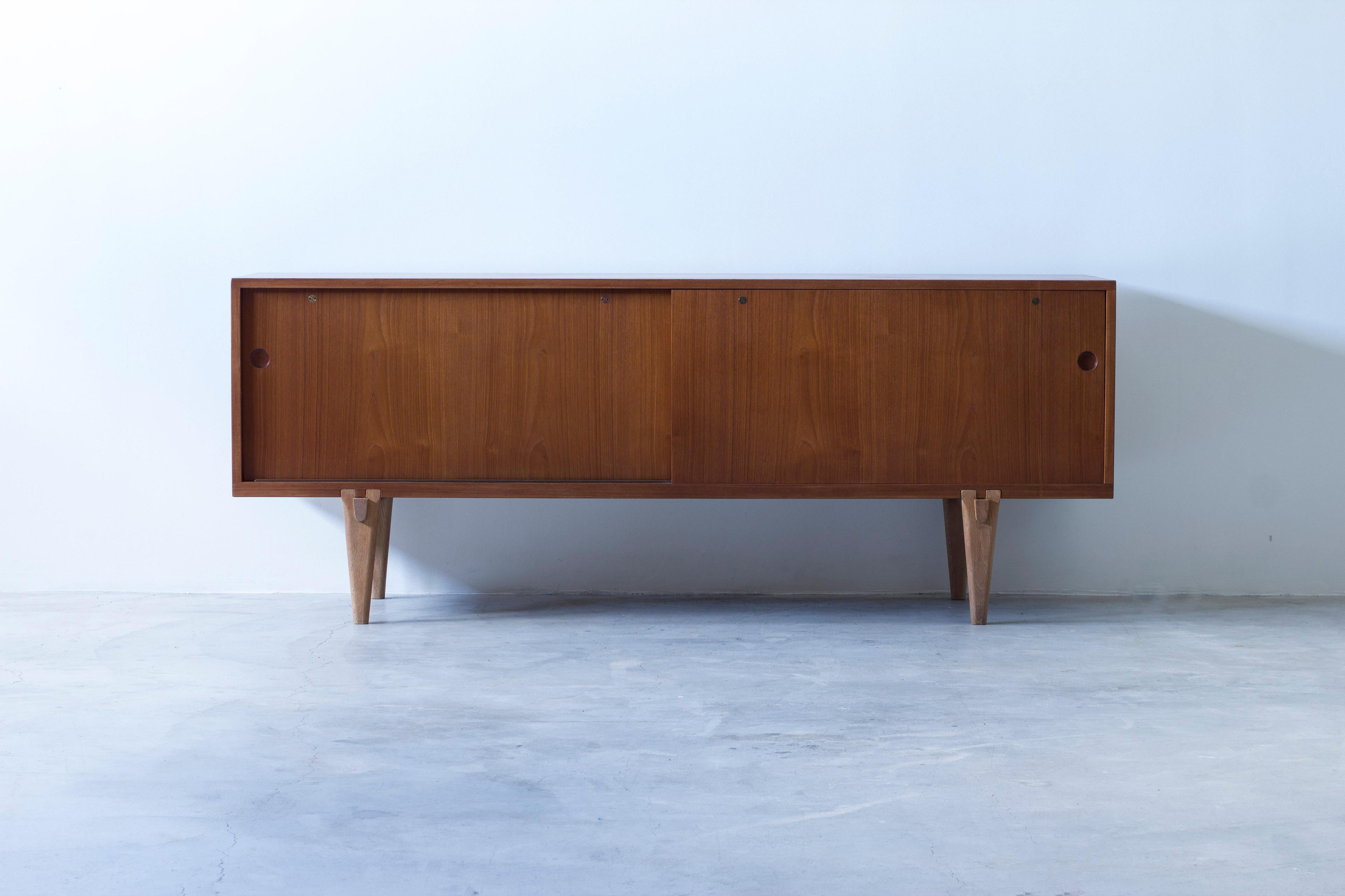Rarissima credenza modello Ry-26 disegnata da Hans J. Wegner con insolite gambe a forma di puzzle triangolare. Realizzato in Danimarca da Ry Møbler negli anni Cinquanta. Il mobile è realizzato in impiallacciatura di teak con interno in rovere chiaro