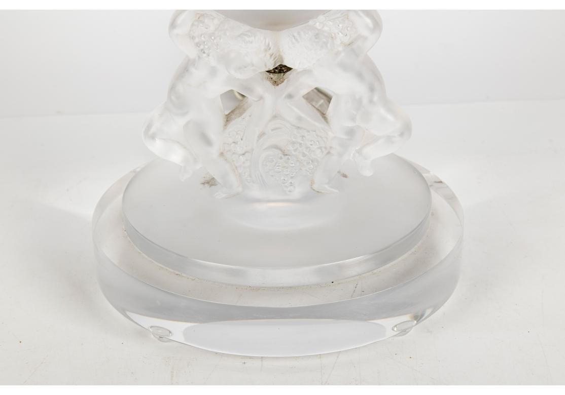 A rarely seen and fine Lalique Lamp design. Signed on the base. A charming footed bowl or vase with two frosted glass putti dancing with grape clusters as the support on a circular base. With newer mounts as a twin light table lamp on a round