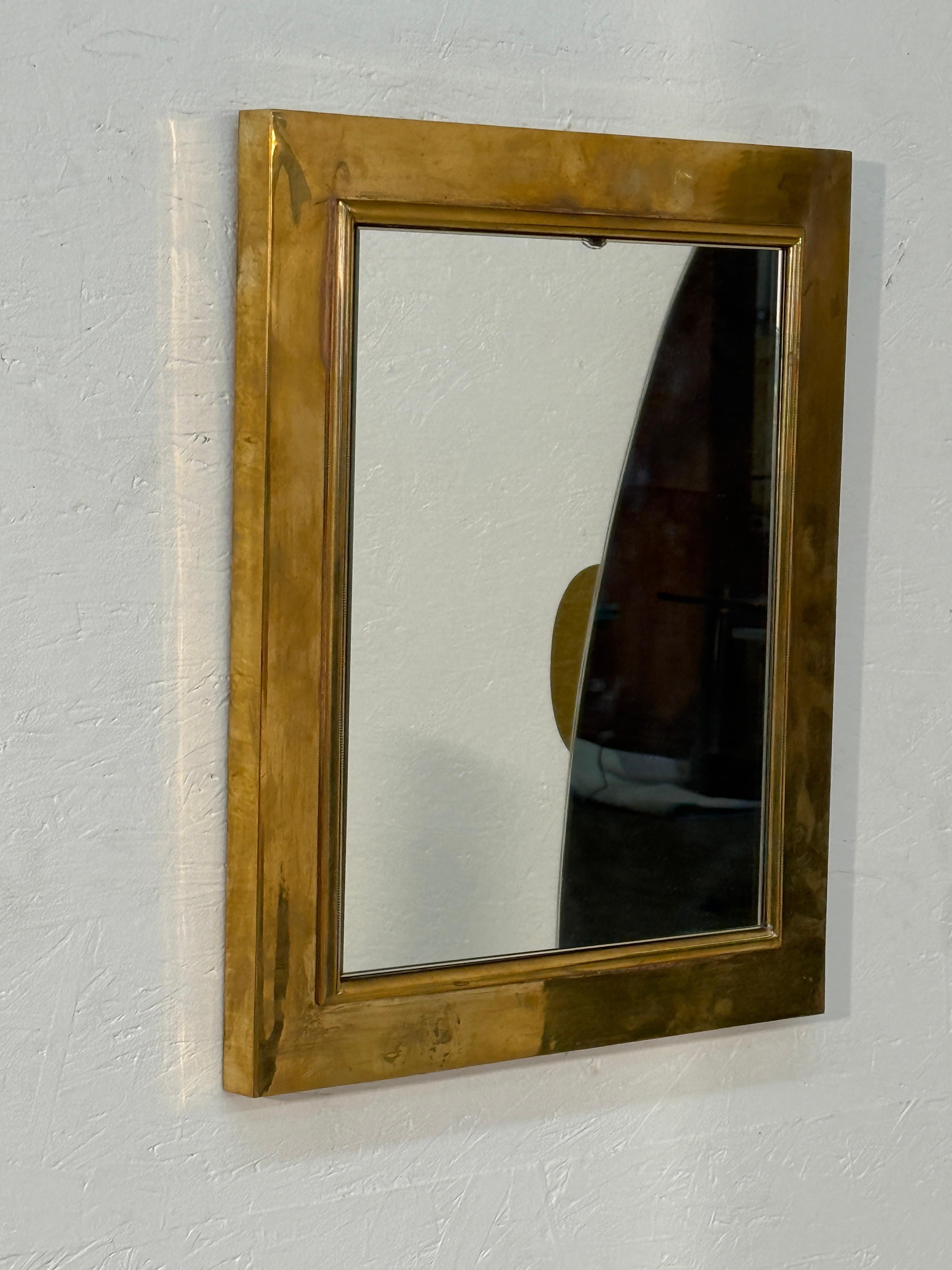 A rare refined rectangular wall mirror encased in a wide solid brass frame. The mirror’s clean, geometric lines are enhanced by the warm patina of the brass, giving it both strength and elegance. Its timeless simplicity allows it to complement a