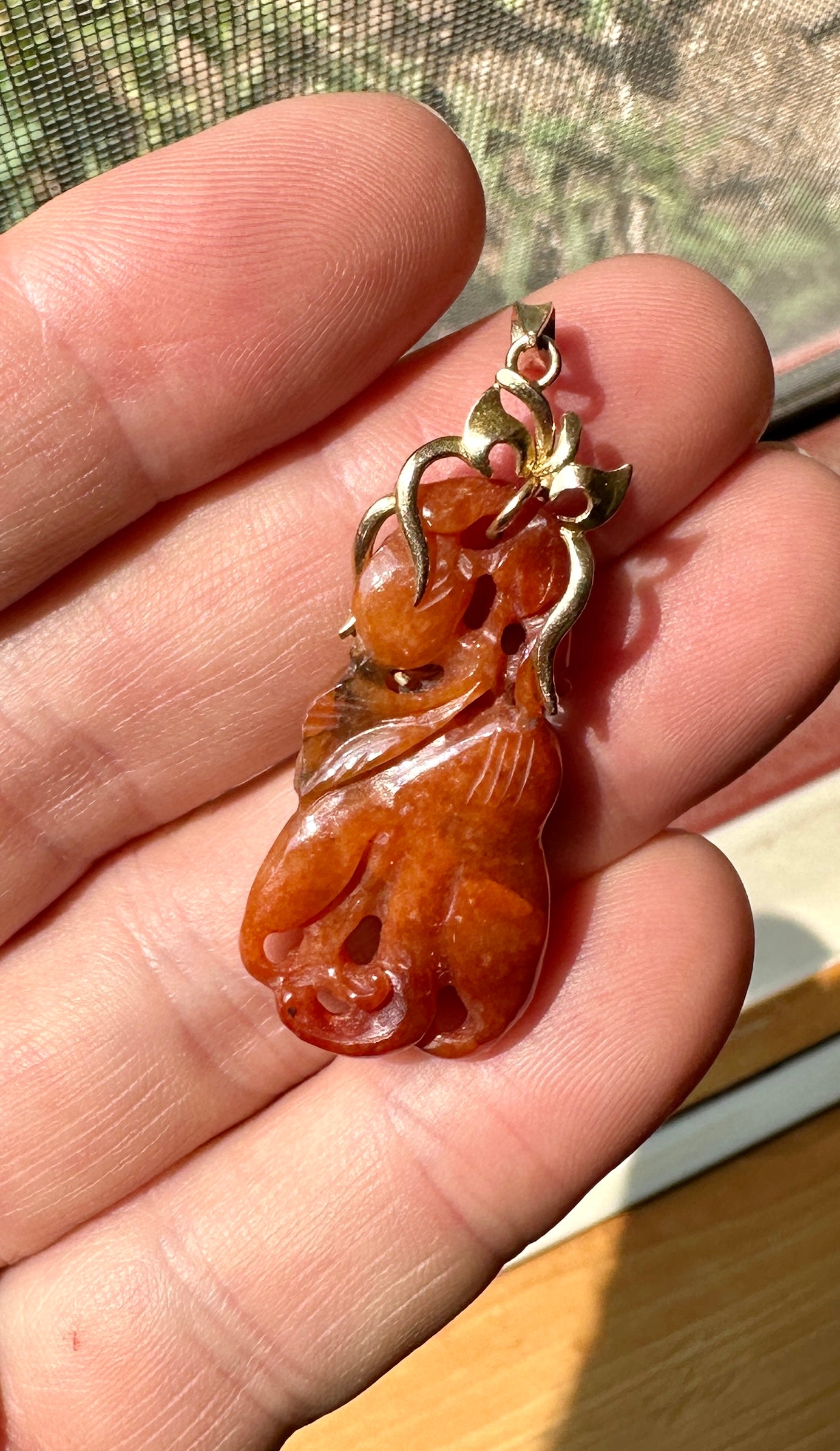 THIS IS A VERY RARE RED JADE FLOWER PENDANT.  THE MAGNIFICENT RED JADE IS BEAUTIFULLY CARVED IN A HANGING FLOWER MOTIF AND IS SET IN AN ELEGANT SCROLLING SURMOUNT IN 14 KARAT YELLOW GOLD.
The meaning behind the jade flower and leaf carving is that