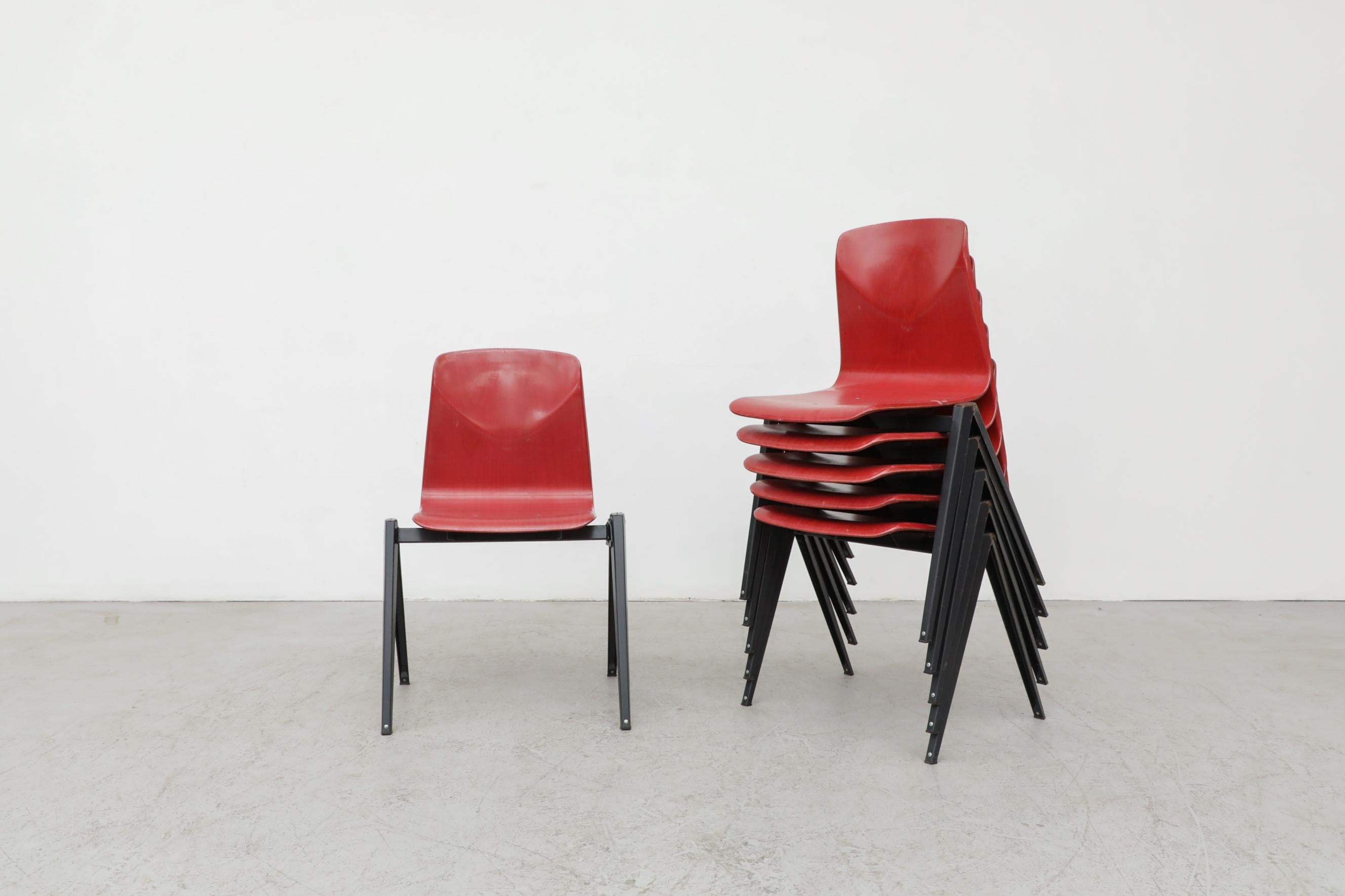 Chaises empilables industrielles de style Prouve avec assise en coquille de style Hansen en rouge et piétements en métal émaillé foncé par Galvanitas. Des liens créatifs pour faire des rangées. En état original avec patine visible. L'usure est