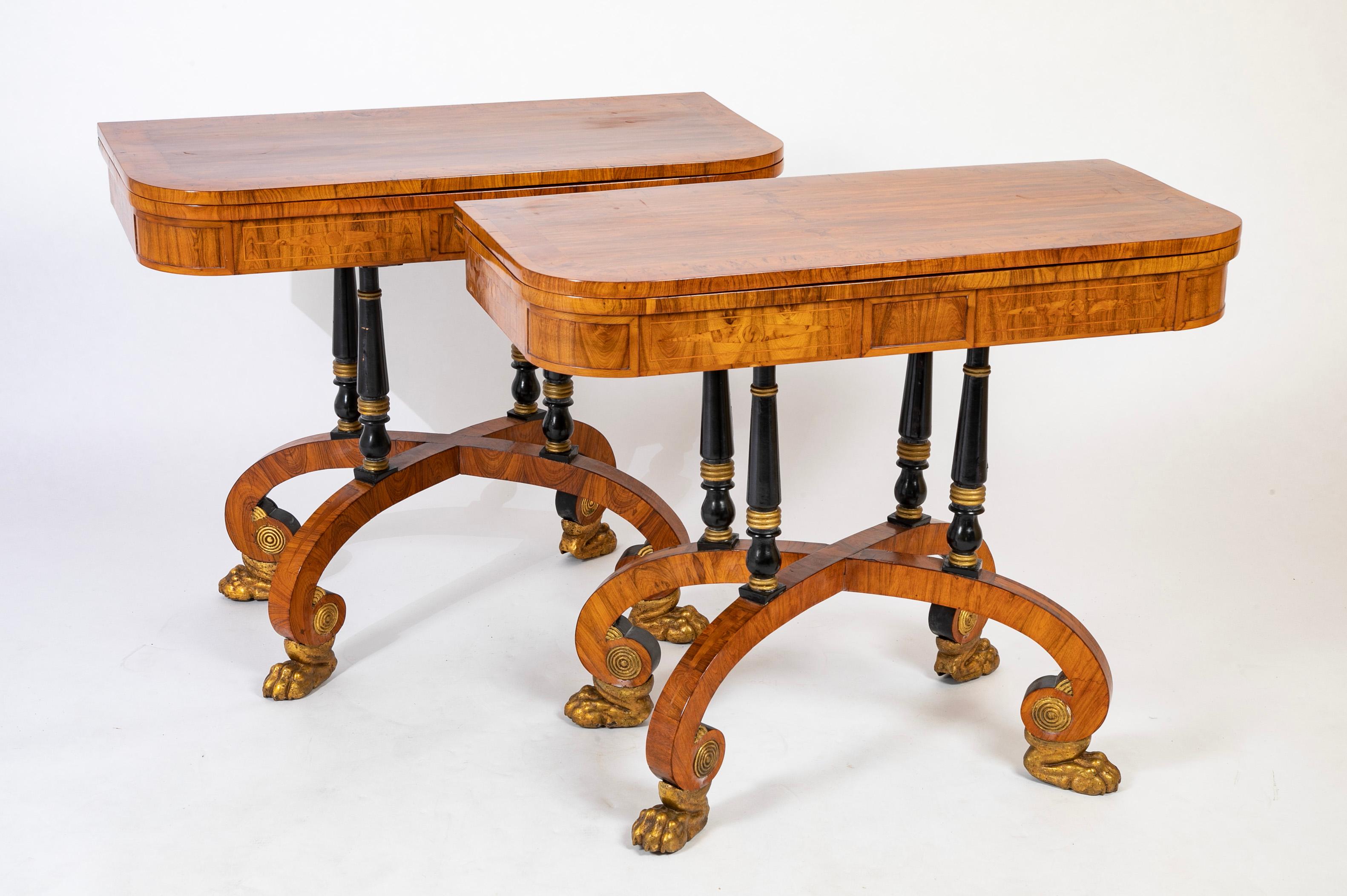 Rare Regency pair of games tables of rosewood and burl leather games interiors over unusual scroll legs and gilded paw feet.   Games pieces included.    Circa 1820.