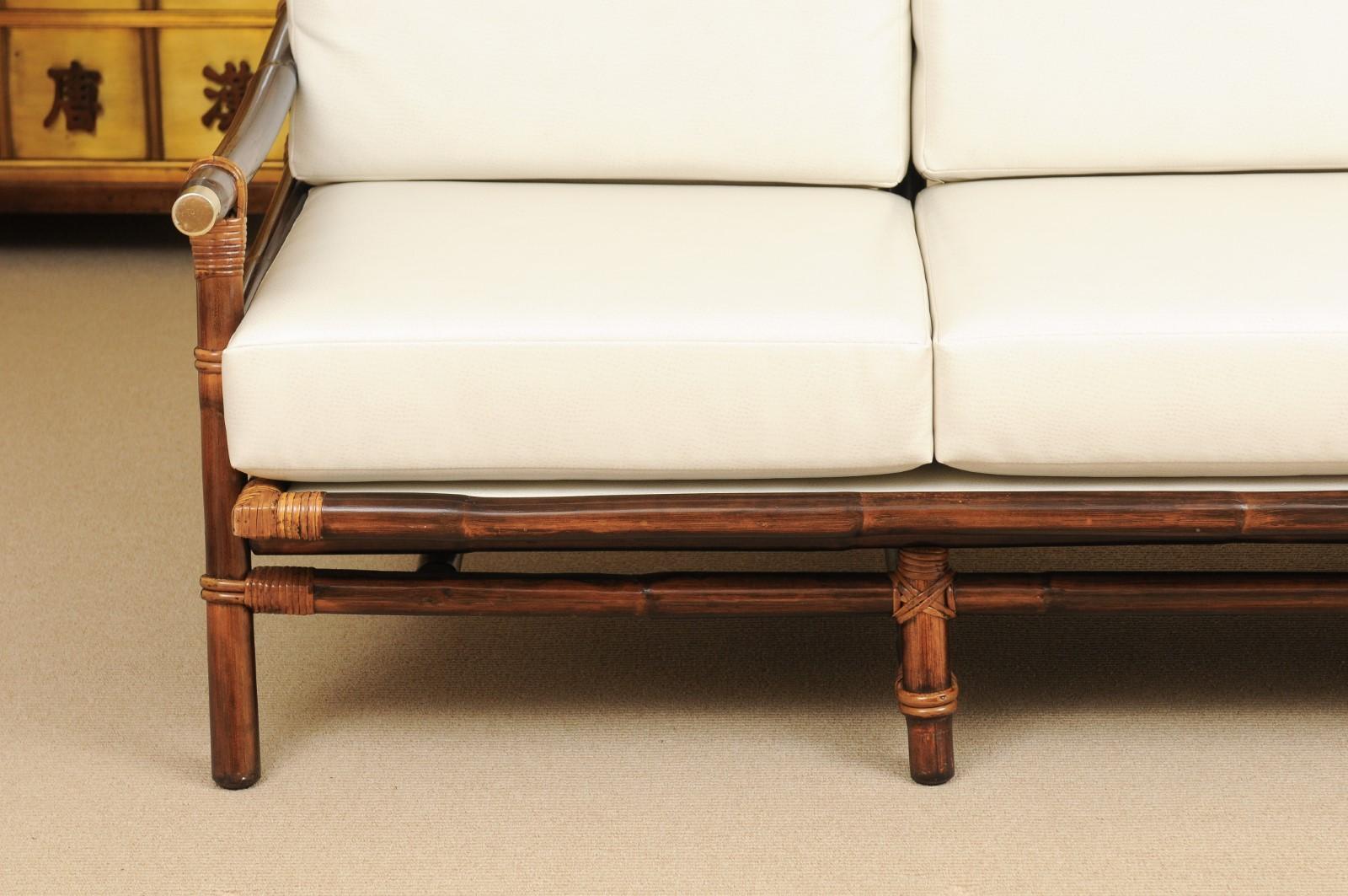 A fabulous restored vintage Campaign style sofa from a difficult to find series by John Wisner for Ficks Reed. Exceptional rattan and hardwood construction with Cane back panels. Brass caps accent the arms. Aged to absolute perfection. The