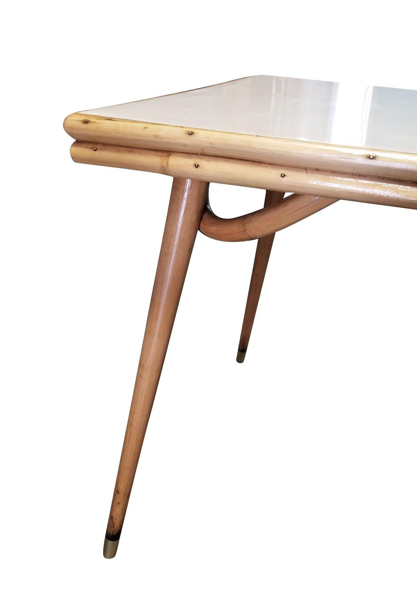 This beautifully restored Paul Frankl-inspired Mid-century single-strand rattan dining table. The table is made with a large formica top held up with a rare single-strand sculpted tapered leg each leg finished with a brass foot. This piece combines