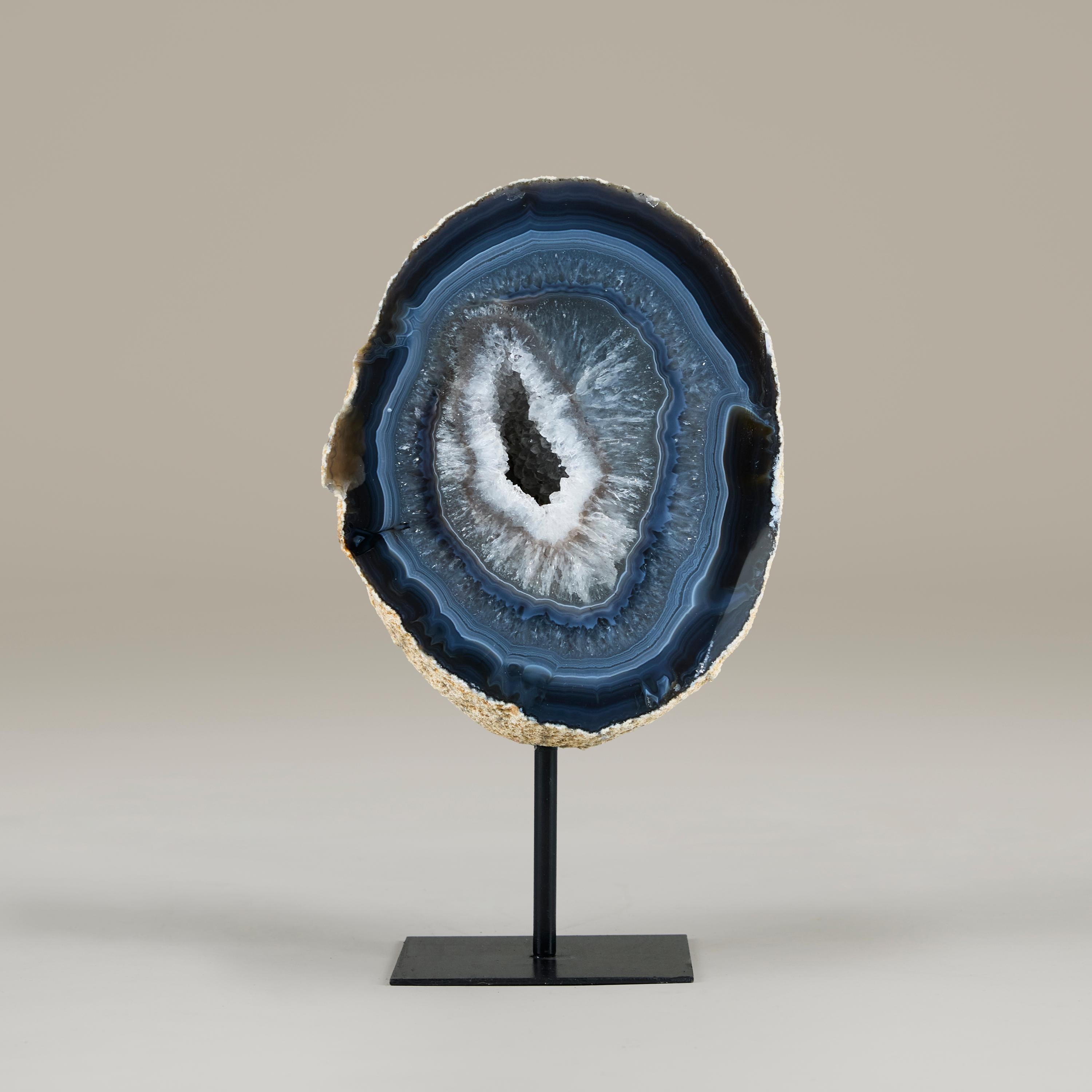 Raras y bellas obras de arte de la naturaleza. Geoda de ágata bien proporcionada compuesta por azules intensos con encaje blanco y flor de cuarzo. Se apoya en un sencillo soporte de metal negro