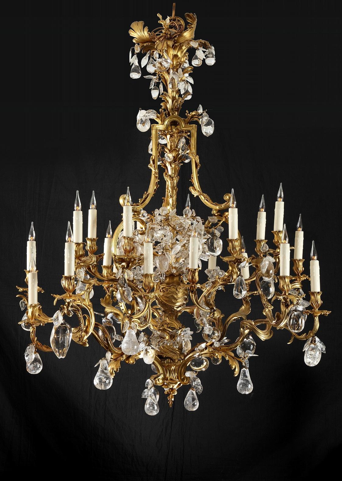 Exceptional ormolu and rock crystal twenty-four-light chandelier attributed to L. Messagé. Made of cage form, the central stem cast with bulrush and a fruit-filled vase, issuing twenty-four scrolled candlearms hung with rock-crystal fruit-form drops