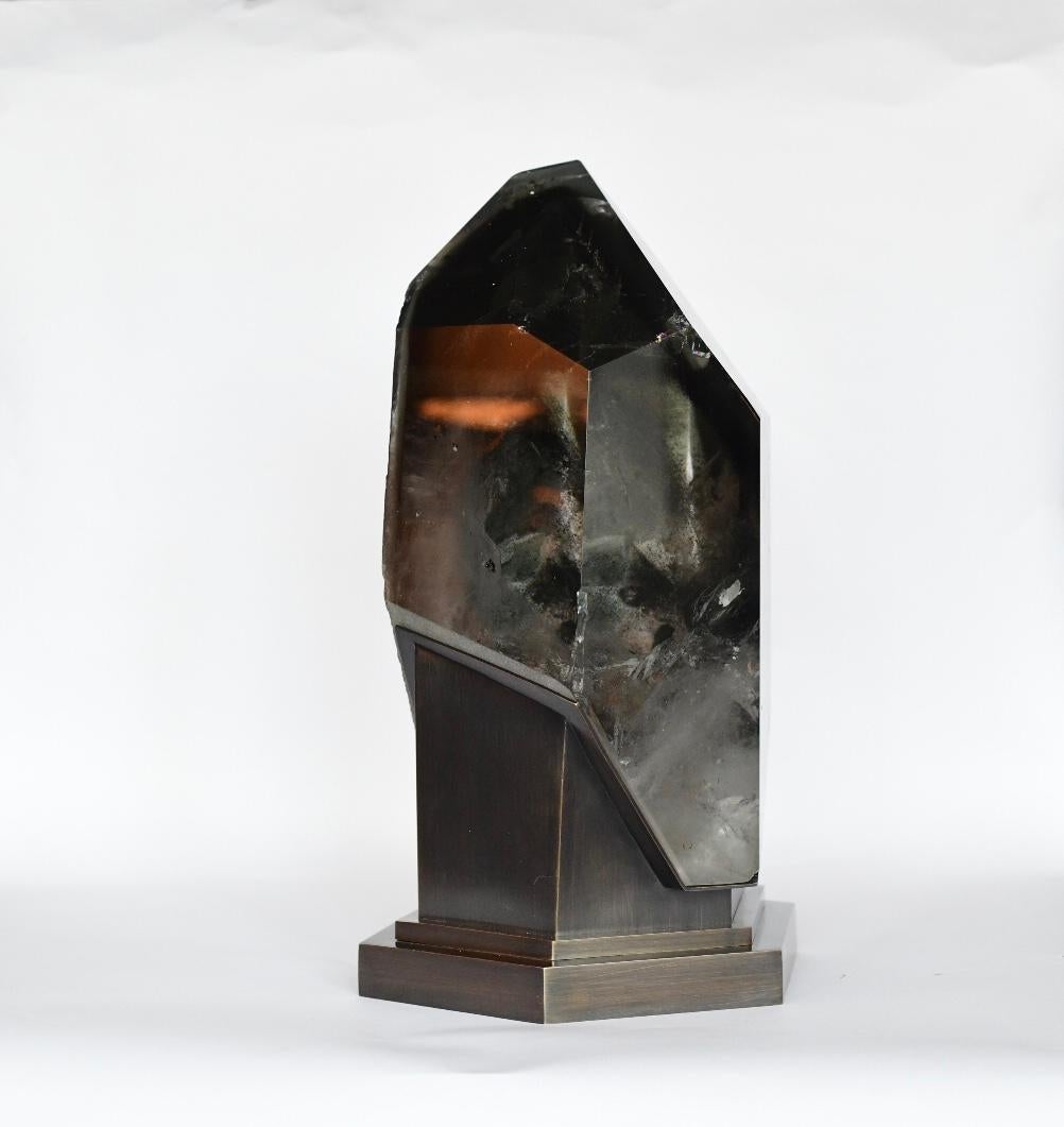 A diamond form rock crystal sculpture light.
A million years old rock crystal that encases the top of a mountain over the clouds. An abstract work of nature. 
Antique brass finish base. Created by Phoenix Gallery.