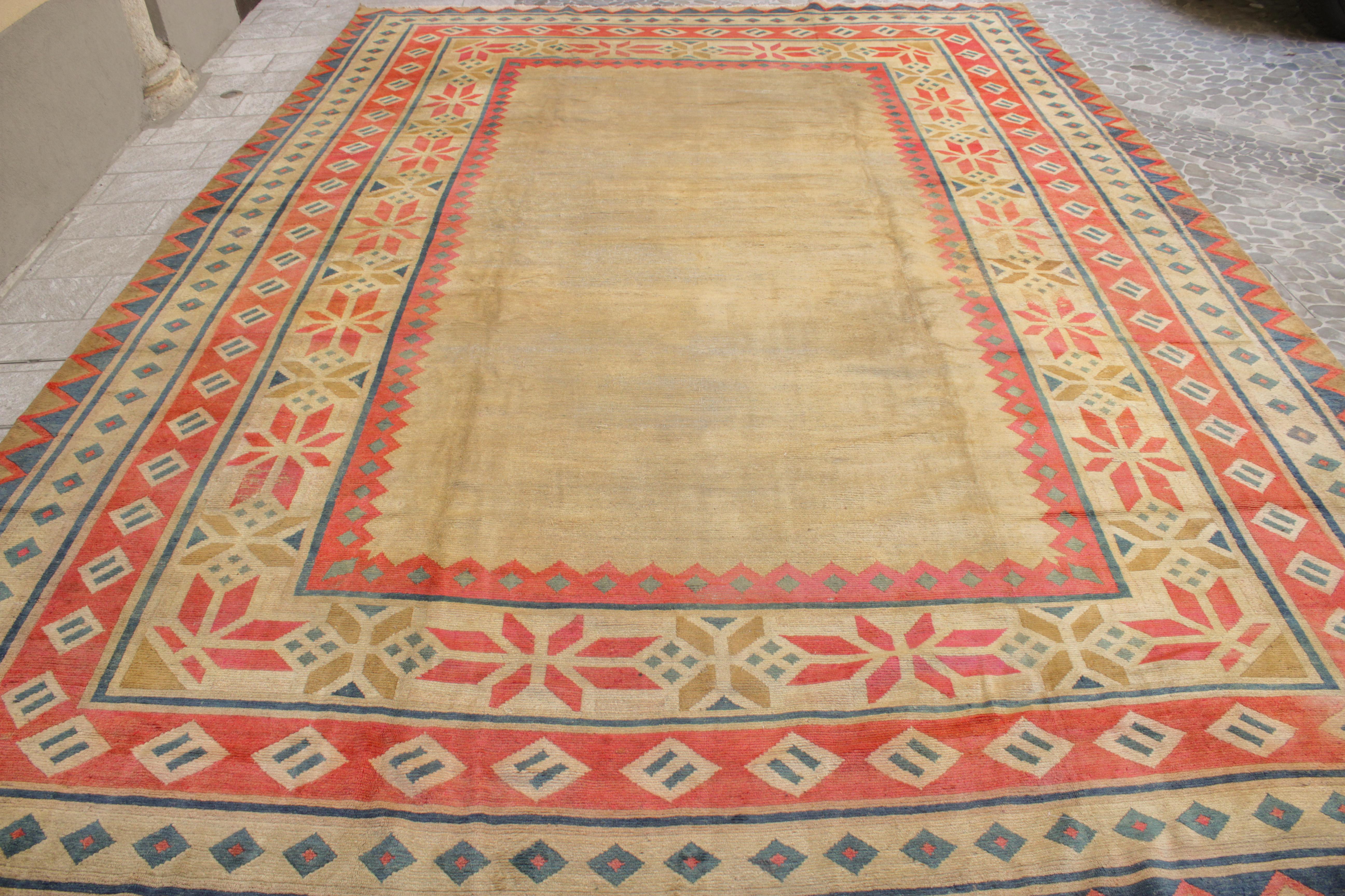 Un tappeto tibetano unico ed elegante di grande formato, molto probabilmente commissionato all'epoca per uno scopo speciale. Il campo aperto neutro è incorniciato da una serie di bordi, il più grande dei quali contiene una serie alternata di