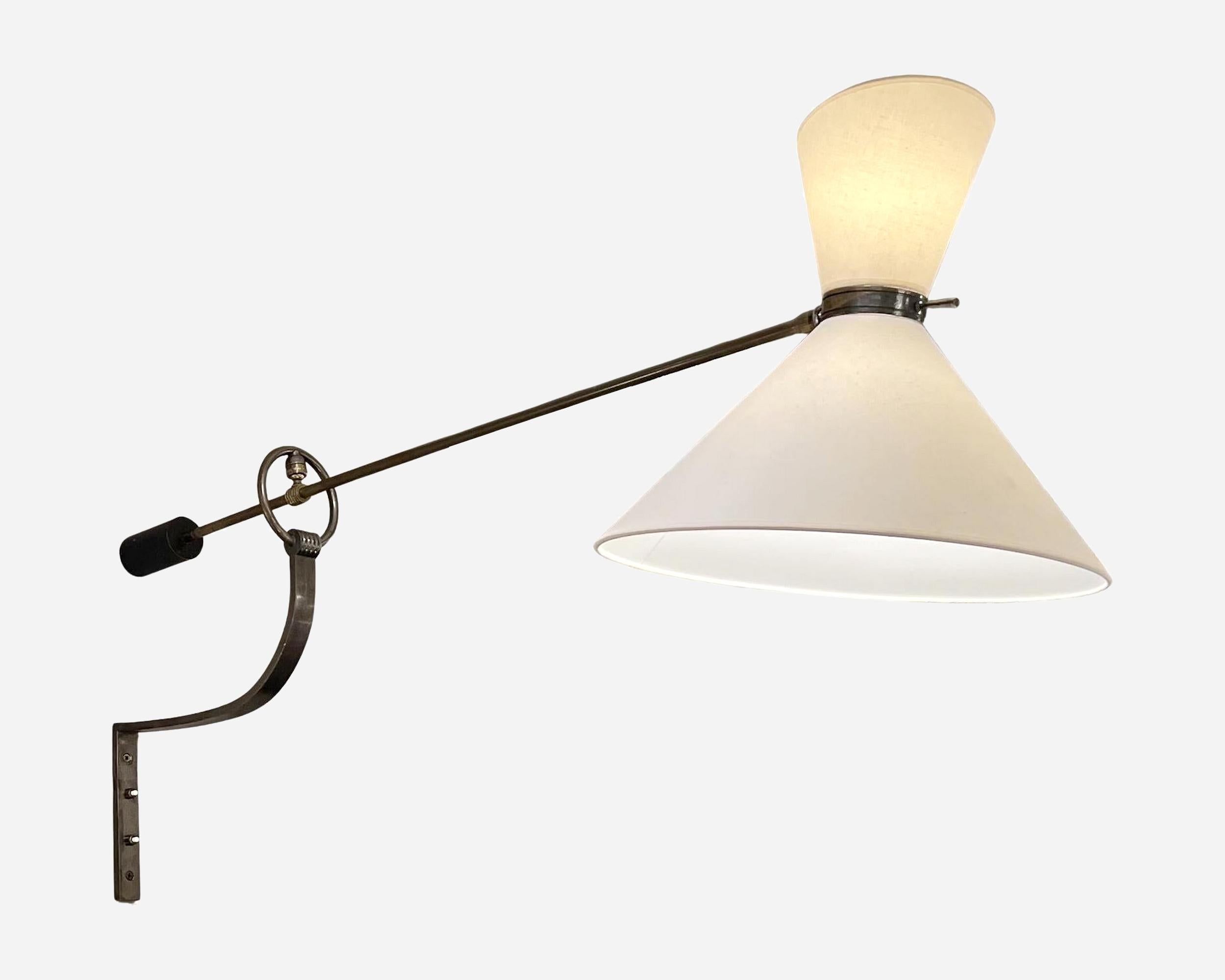 A rare pendulum wall light by Maison Lunel, France, circa 1950. The sconce swivels 180° and at the top, the light arm passes through a ring where it is fixed by a ball-and-socket joint. The shade is also swivel-mounted and adjustable. 