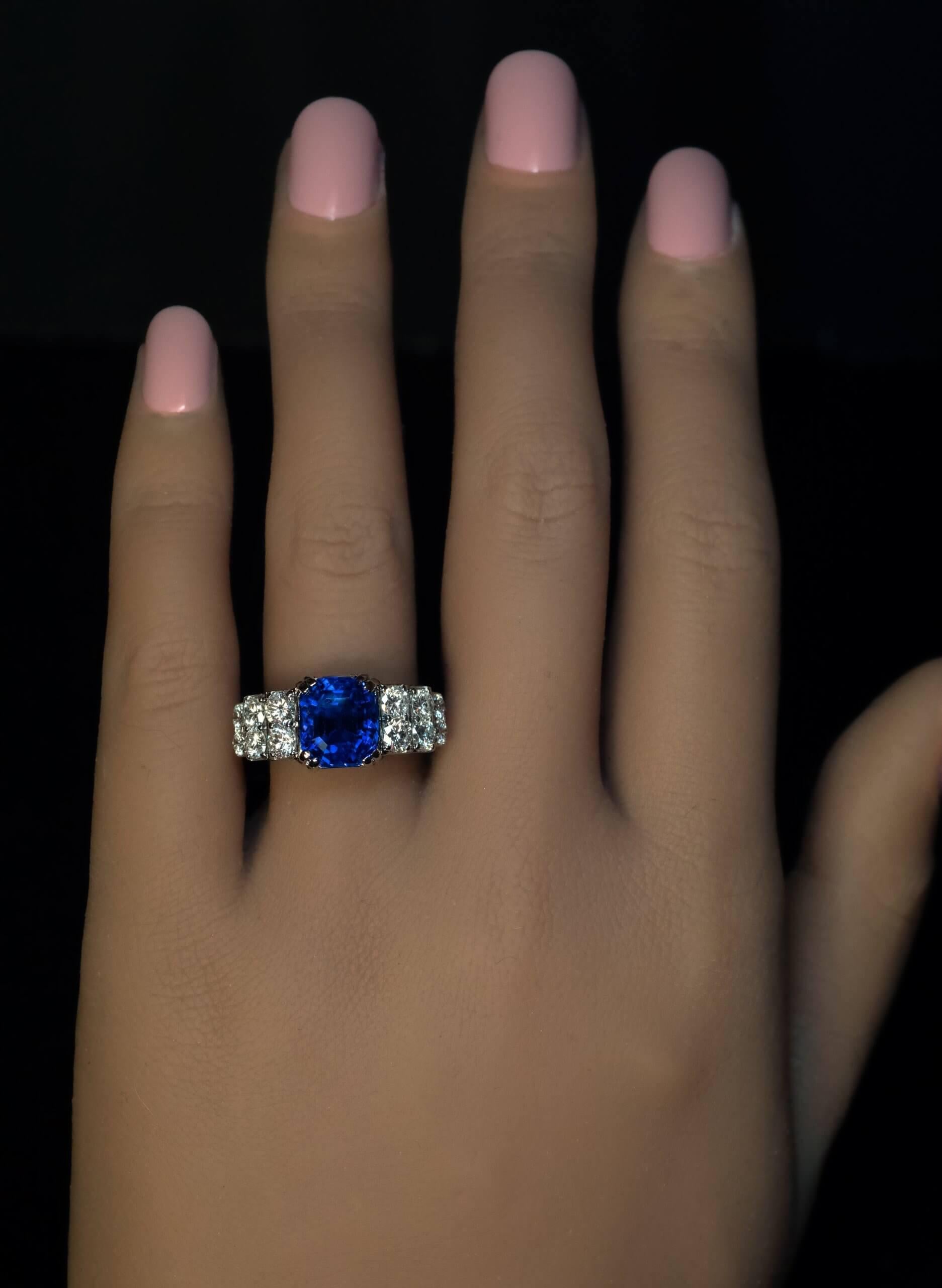 This contemporary 18K white gold ring features a rare 6.21 carat unheated Burmese sapphire of a vivid royal blue color. The sapphire is flanked by six rows of bright white brilliant cut diamonds.  The ring is accompanied by the American Gemological