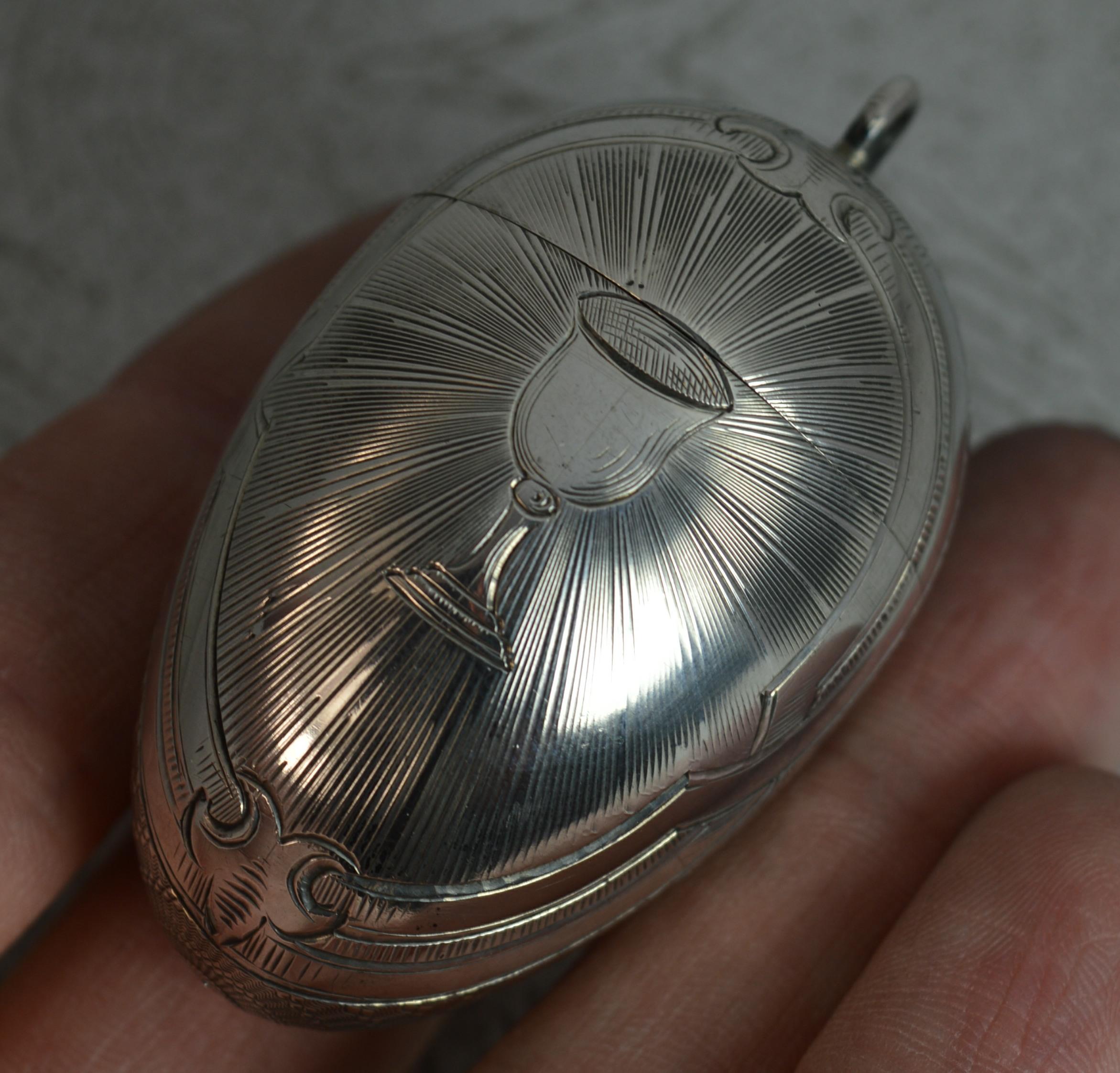 A very unusual and rare egg pendant.

84 grade solid silver example from Russia.

Designed as an egg which screws open to the centre.

A chalice engraving to the centre with with sun rays surrounding. The remaining with a fine engine turned pattern.