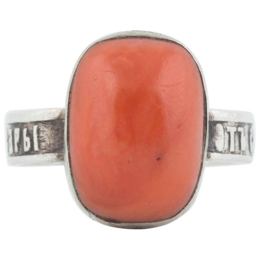 From the Romanov era, period of Tsar Nicholas II, this rare silver ring is bezel set with an orange coral from the Black Sea. The shank is inscribed with a dedication to Saint Barbara in Old Church Slavonic. The coral measures approximately 12 x 8 x