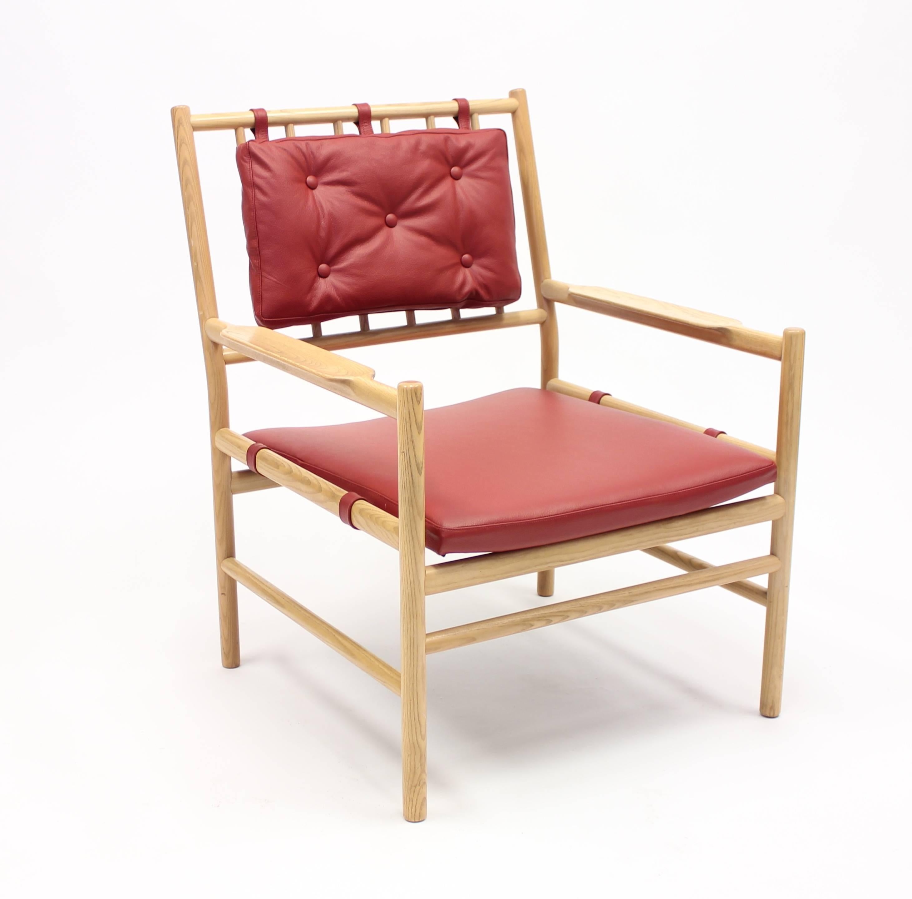 A 1970s Scandinavian midcentury safari style oak easy chair designed by Arne Norell for his own company Arne Norell AB with newly upholstered red leather seat and back cushion. A typical Swedish design, very light in appearance due to the very thin