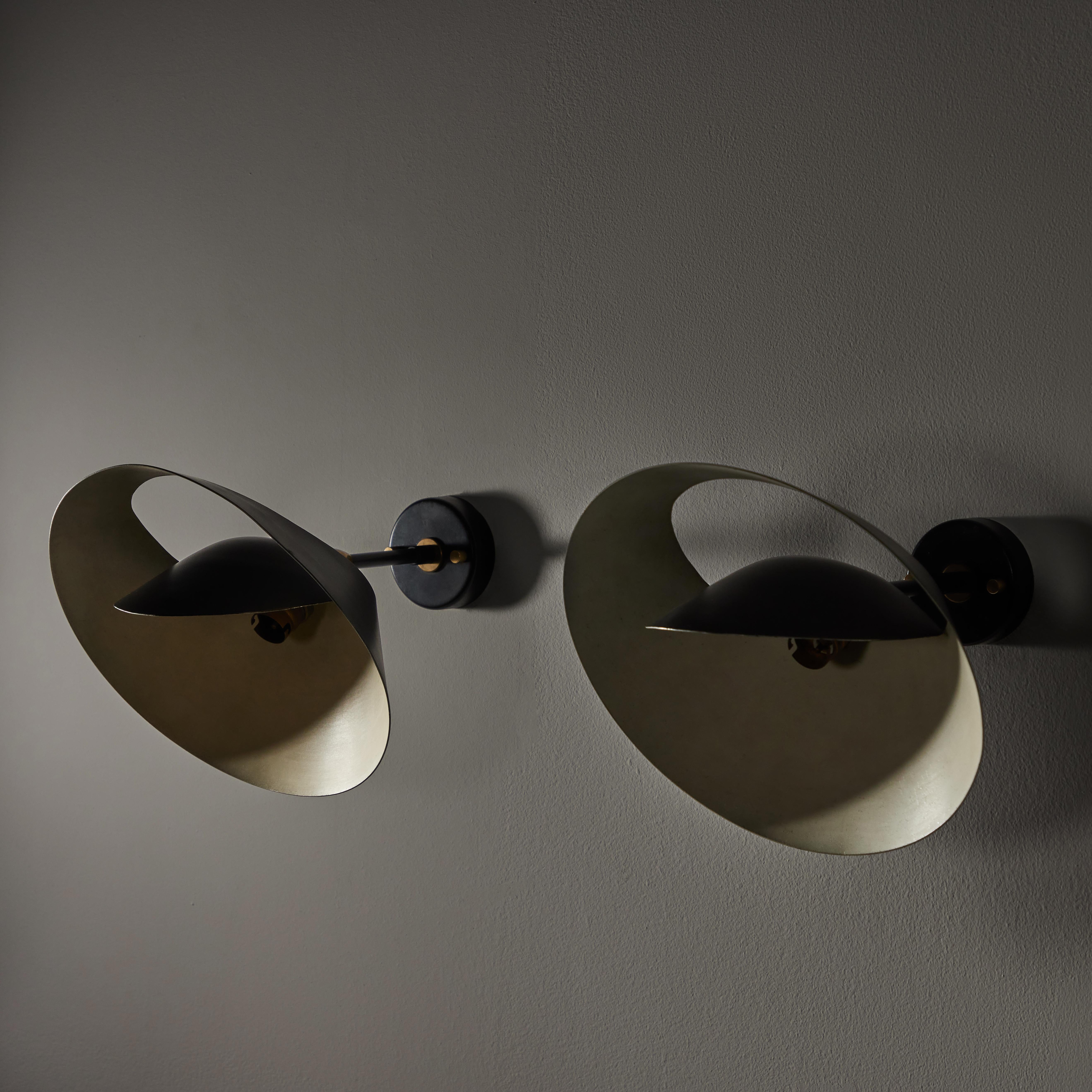 Applique Saturne sconces by Serge Mouille. Manufactured in France, circa the 1970s. Remarkably formed sconces that mimic the orbital rings of Saturn. Similar to other Mouille designs of this era, these rare sconces are constructed of black enameled