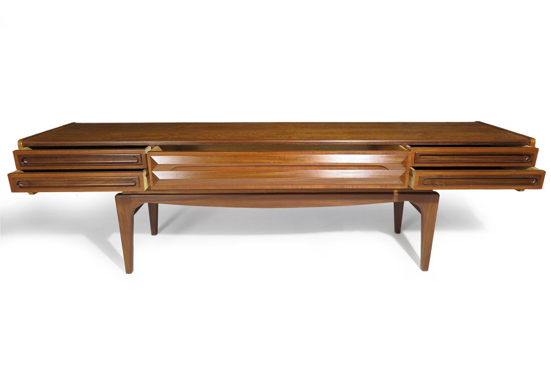 Scandinavian low cabinet attributed Ib Kofod-Larsen, 1955 Denmark. The cabinet is handcrafted of beautifully grained old-growth teak with series of four drawers with sculptured pulls and raised on sculptural tapered legs. Professionally restored in