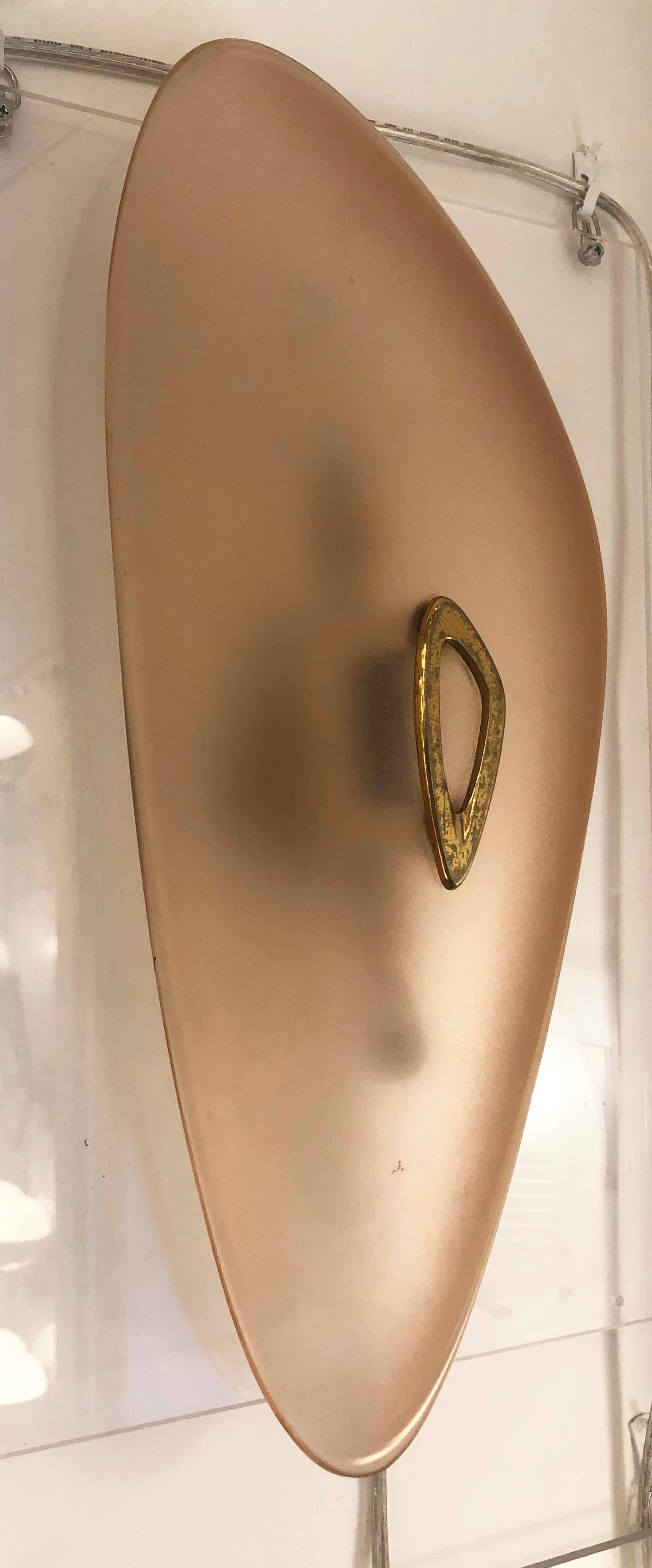 An extremely rare sconce by Max Ingrand for Fontana Arte. There is a brass decoration mimicking the irregular shape of the sconce in the middle of the salmon color frosted glass. The brass frame holds two candelabra sockets.
