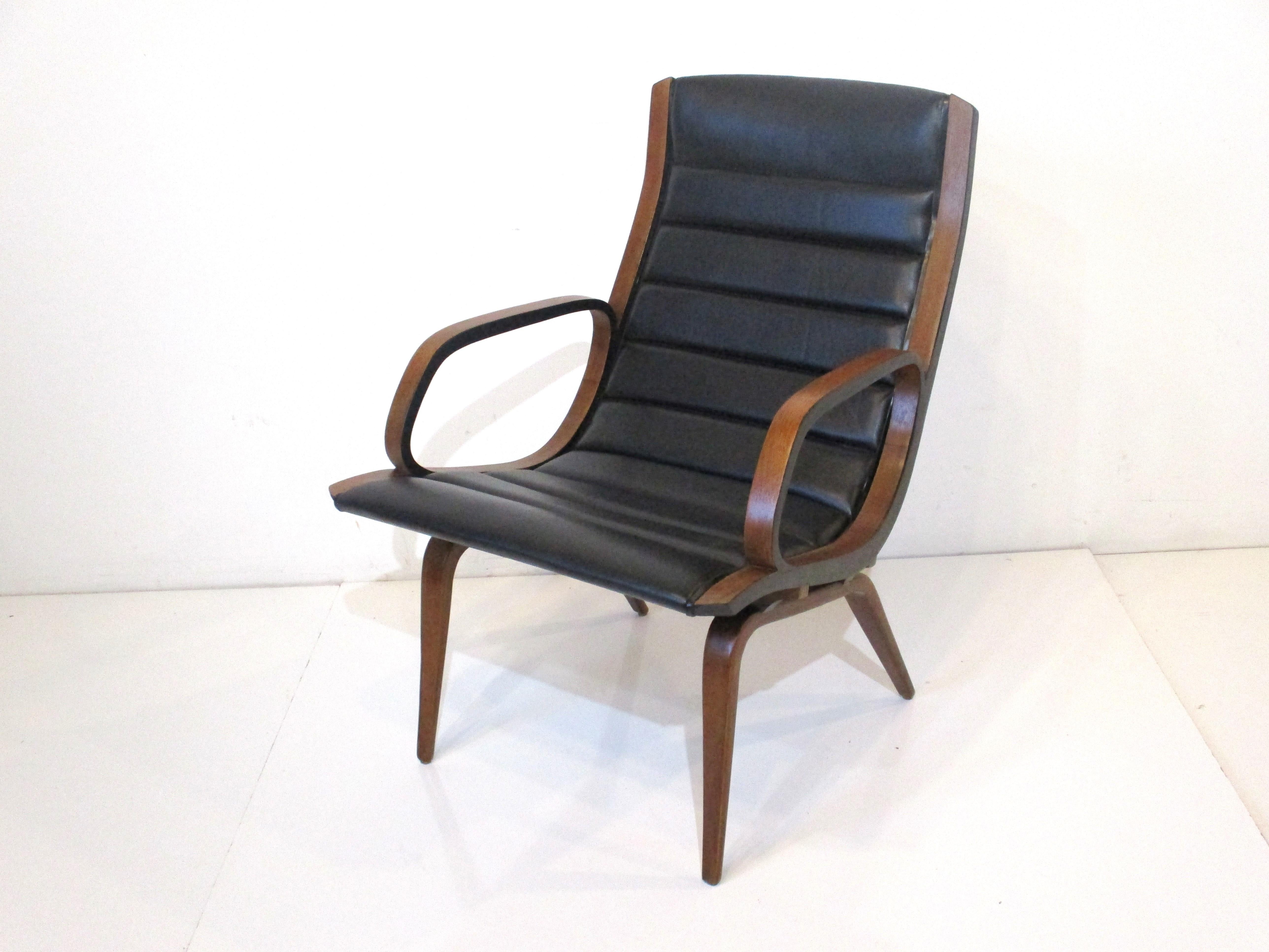 A sculptural bent wood framed arm chair / lounge chair with ribbed black leatherette upholstery. This rare form shares it's DNA with the other pieces designed by Norman Chener with a light visual feel, plenty of comfort and very sturdy construction.