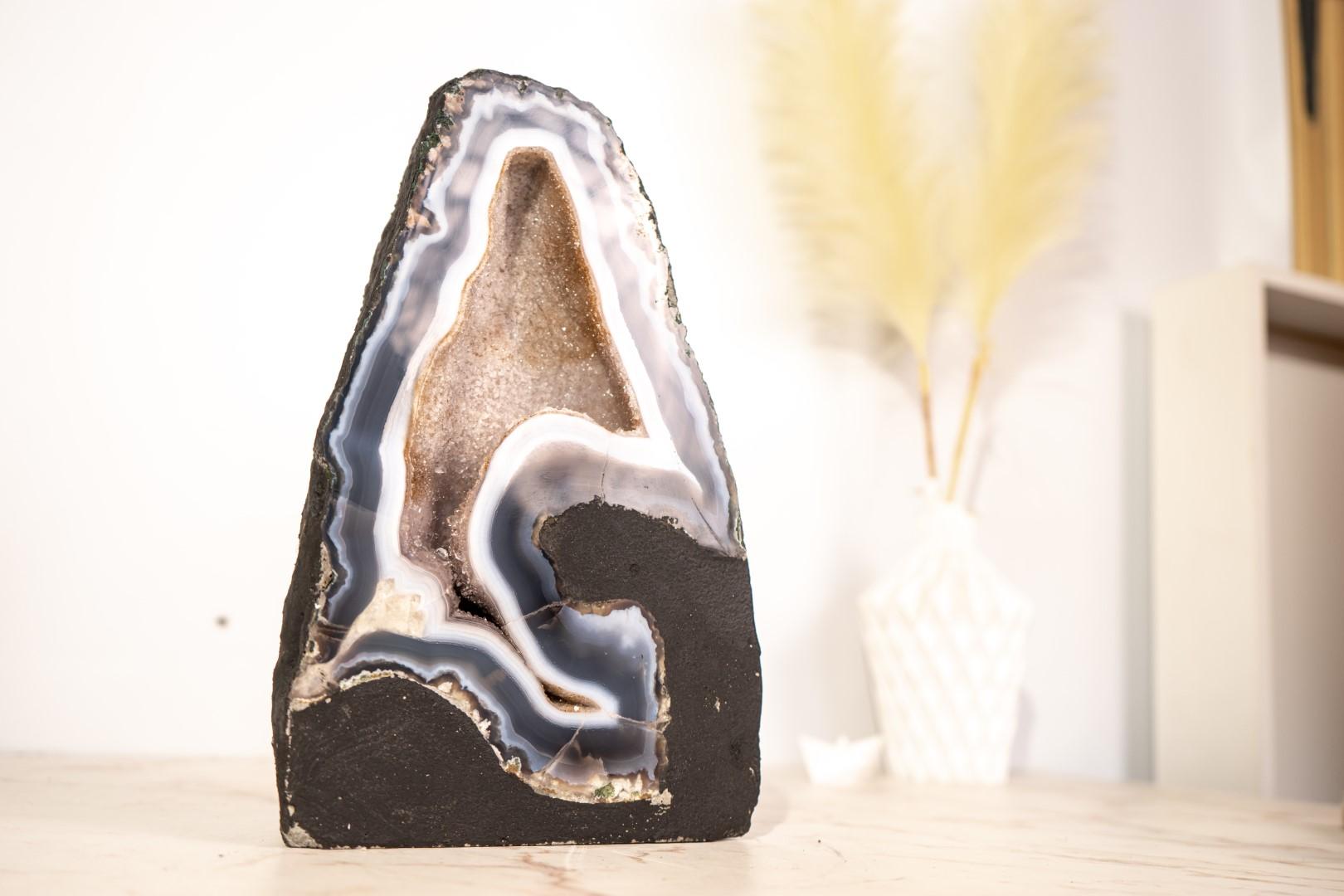 Esta geoda de ágata excepcionalmente rara, grande y hermosa elevará sin duda tu colección o tu espacio. Se trata de una pieza espectacular, meticulosamente cortada para mostrar los motivos de encaje azul y blanco que rara vez se ven, una auténtica