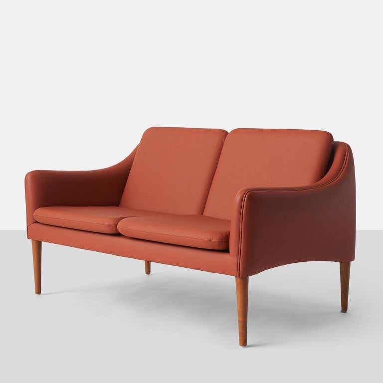 A series 800 settee by Hans Olsen. The settee has been recovered in a persimmon colored leather. 
