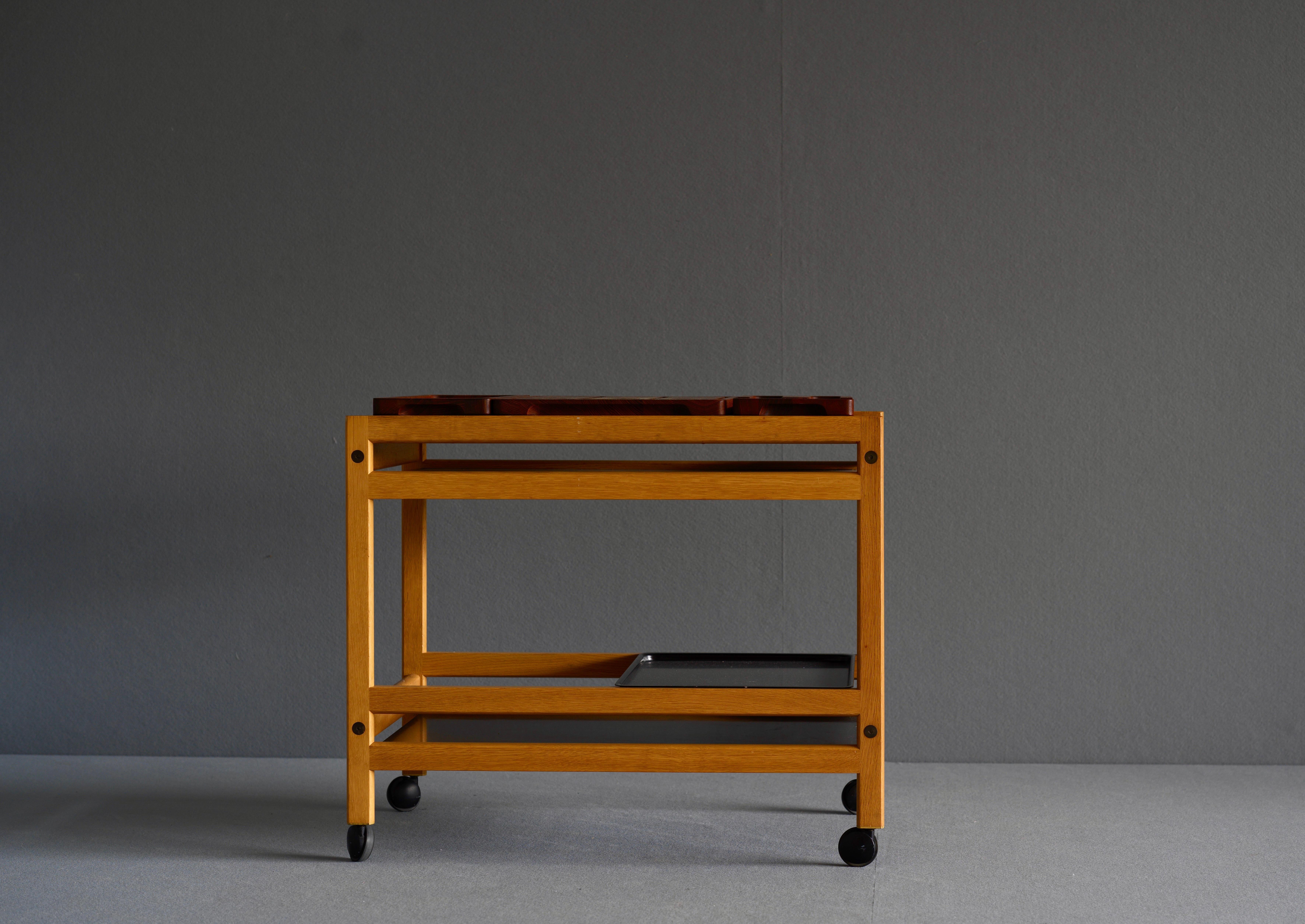 Serving trolley by Borge Mogensen for Fredericia. It is in oak and has shelves in black Formica with 3 loose cutting boards in teak and a metal tray. Circa 1963. The original makers stamp remains. 

Measures: H65 L 78 D52.
 