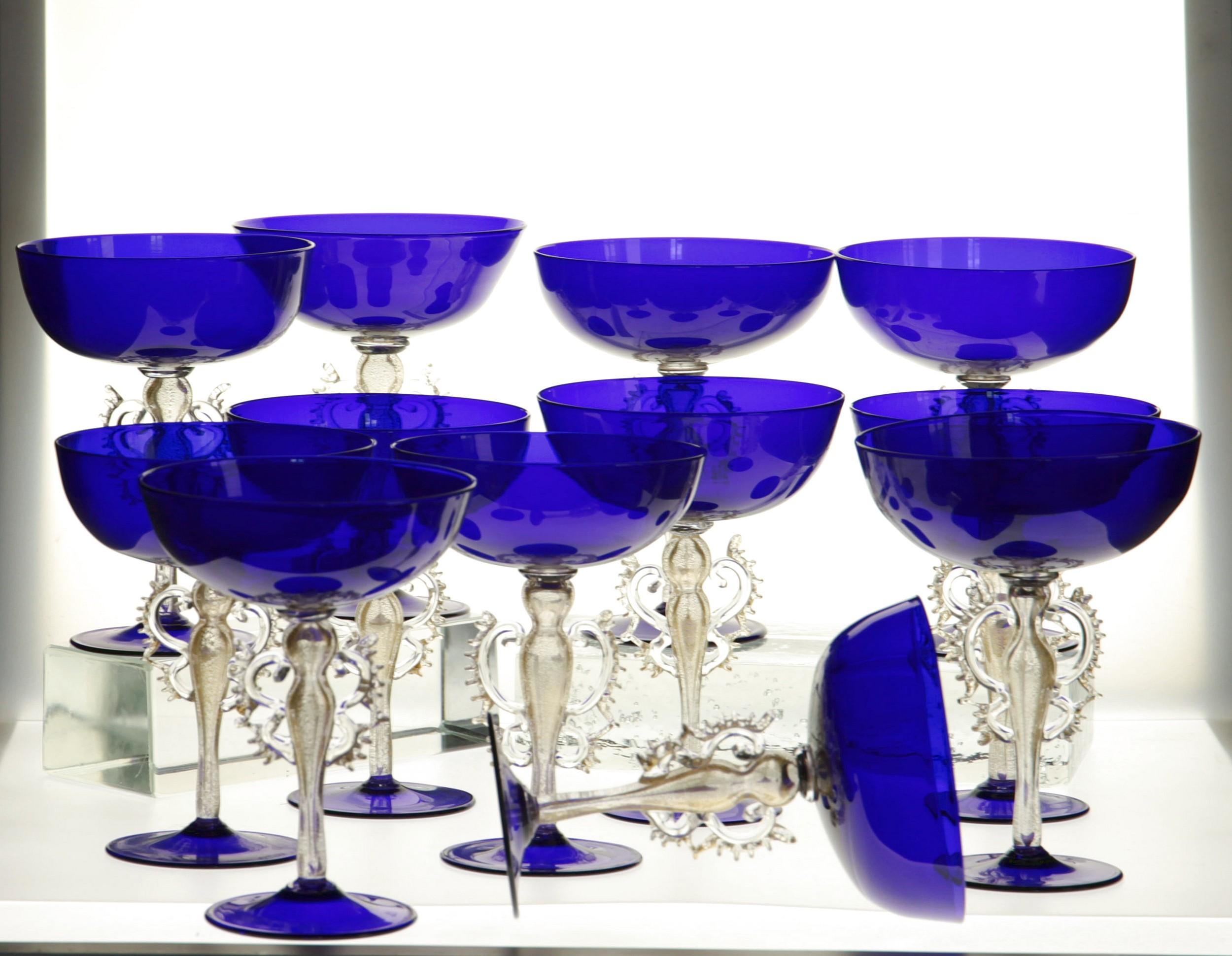 Äußerst seltener Satz von Glaspokalen.

Die Tasse und der Fuß sind kobaltblau gefärbt. Diese Art von Becher wurde in den 50er und 60er Jahren als Champagnerglas bezeichnet.

Jedes Glas ist mit einem komplexen Barockmotiv auf dem geblasenen Stiel
