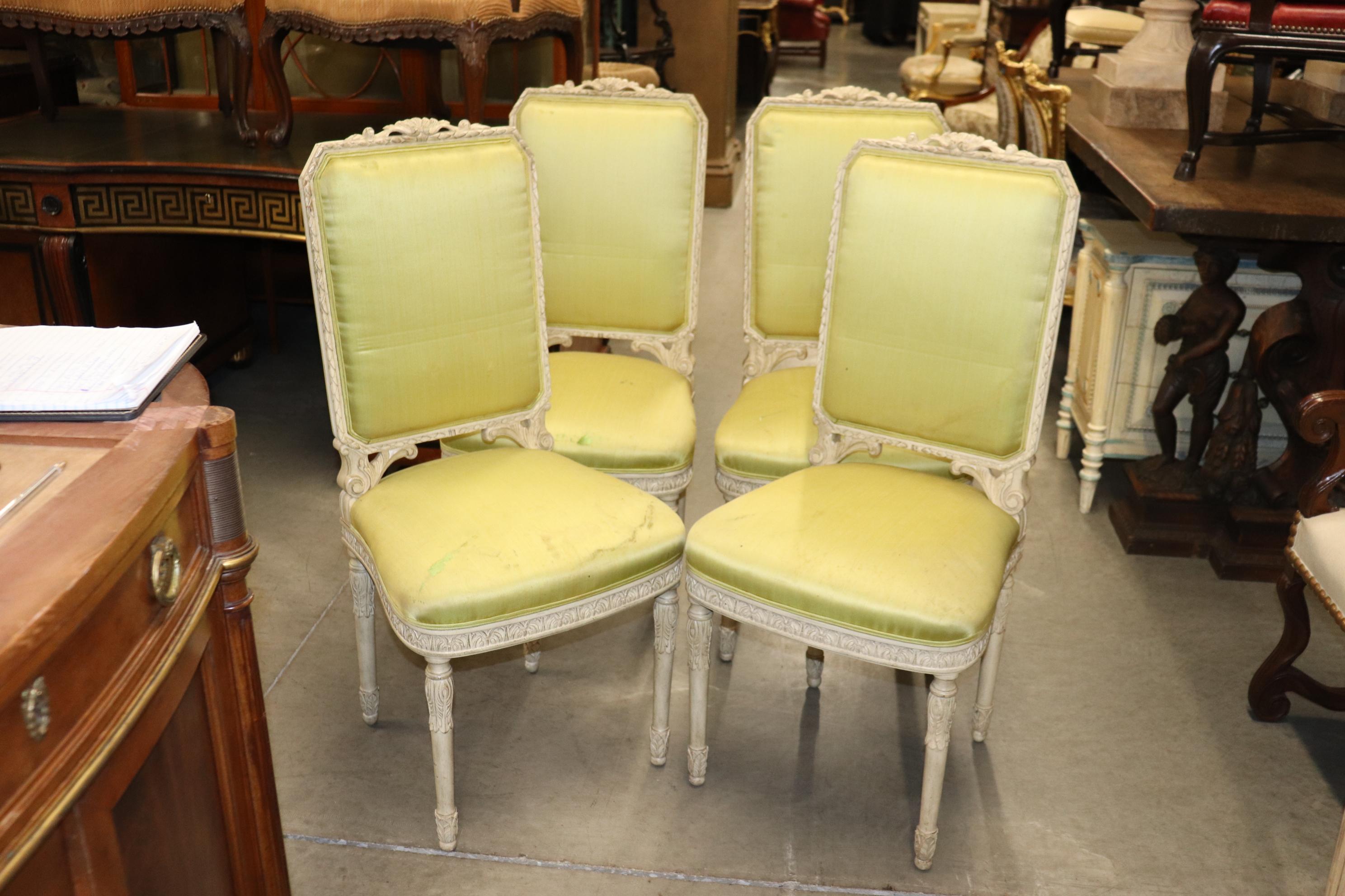 This is a rare set of fine French Louis XVI Maison Jansen style dining chairs. They are in their original silk upholstery it does show ear and signs of use. The frames are done in an antique white with restrained cavred details and simple and yet