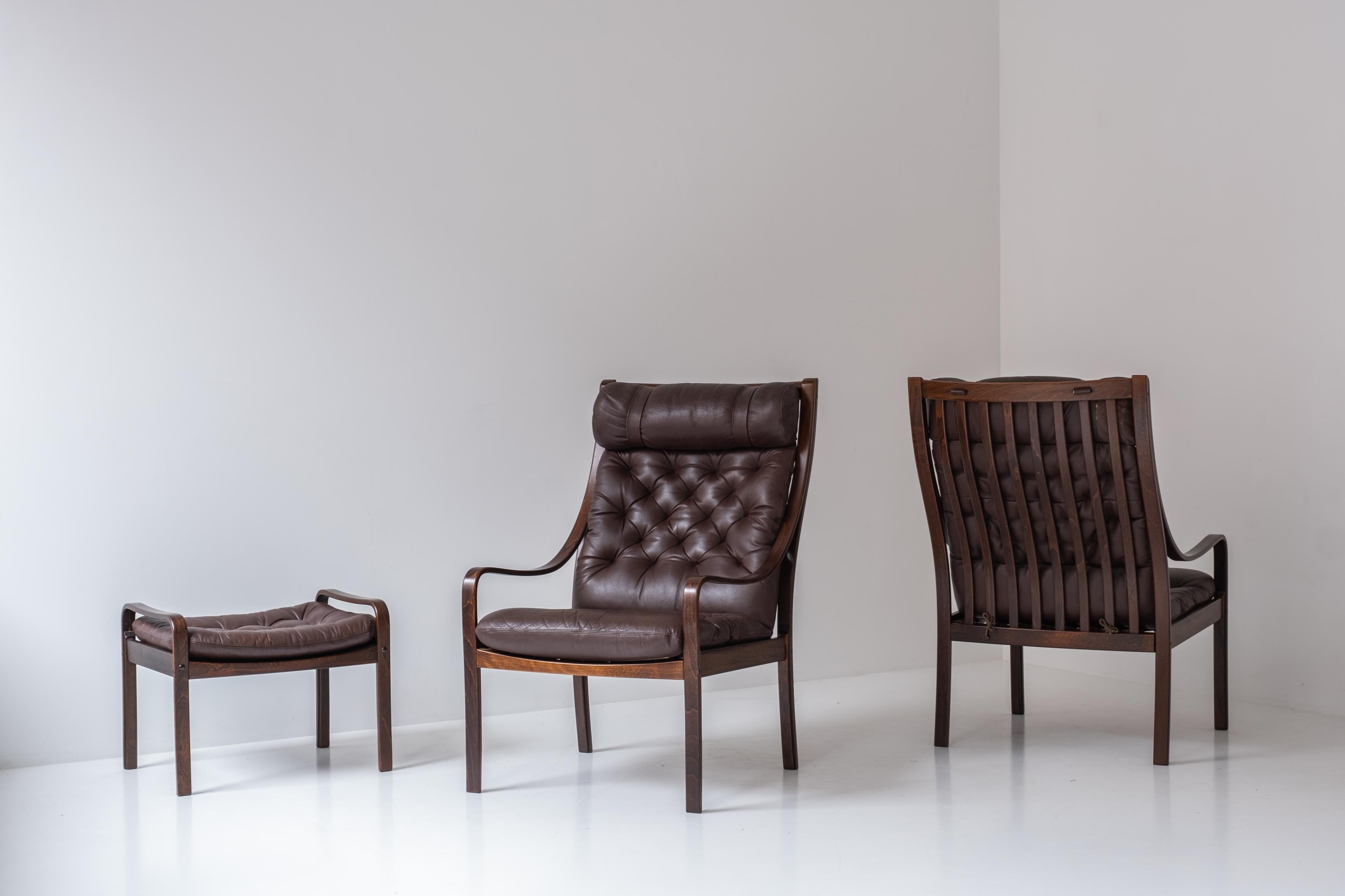 Rare set armchairs and ottoman by Fredrik A. Kayser for Vatne Möbler, Norway 1960s. This set consists of two armchairs and one ottoman. This seating group features a brown leather upholstery and a stained elmwood frame, creating a sophisticated and