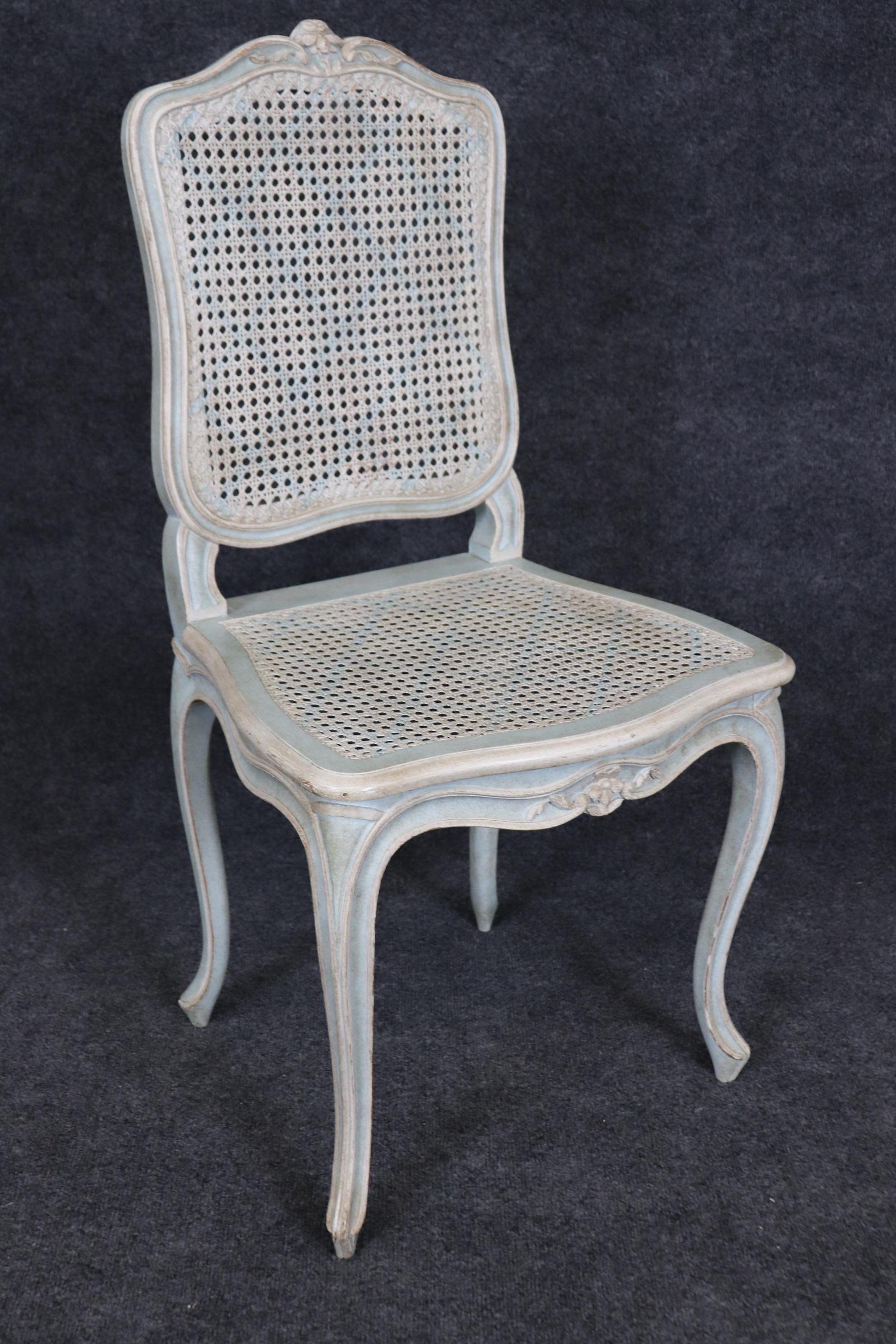 This is a rare robin's egg blue and creme paint decorated set of 12 cane chairs. The chairs have age-appropriate distressing and wear. One chair has a large hole in it and will need to be either repaired or upholstered. Measures 37 tall x 19 wide x