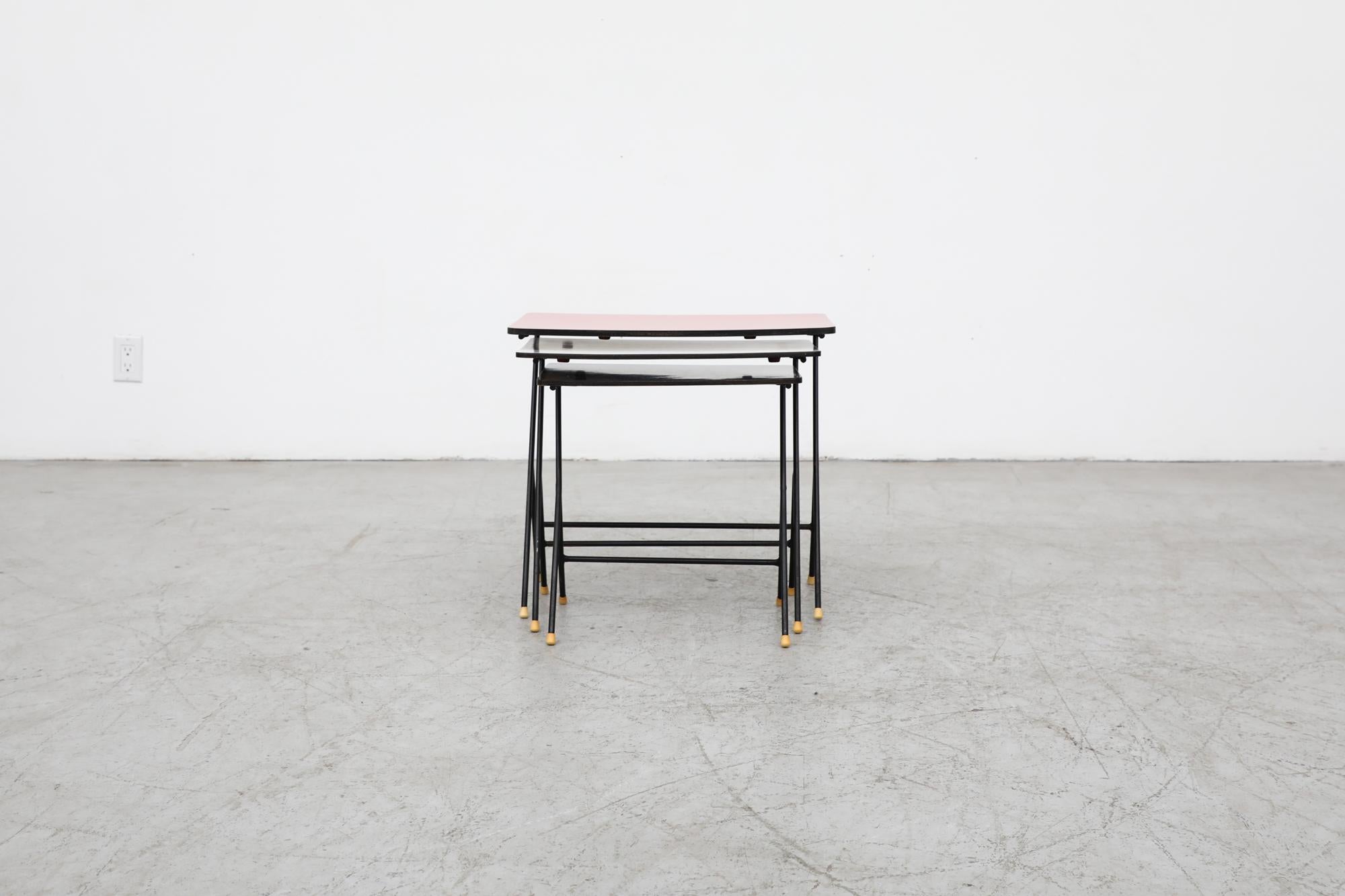 Rare 1950s Pilastro nesting tables with black enameled frames. Table tops are red, bone and black. In original condition with visible wear including enamel loss and minor bowing of the tops. Wear is consistent with their age and use.