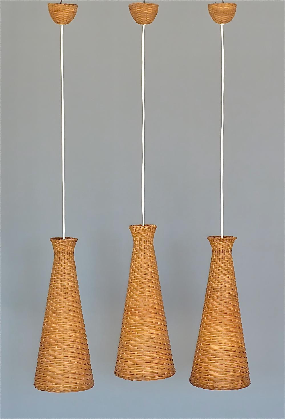 Rare set of three large diabolo rattan / wicker pendant lamps, Swedish / Scandinavian designer around 1960. The lovely and highly decorative Mid-Century Modern diabolo hanging lights are beautifully hand-crafted, hand-woven rattan body fixtures and