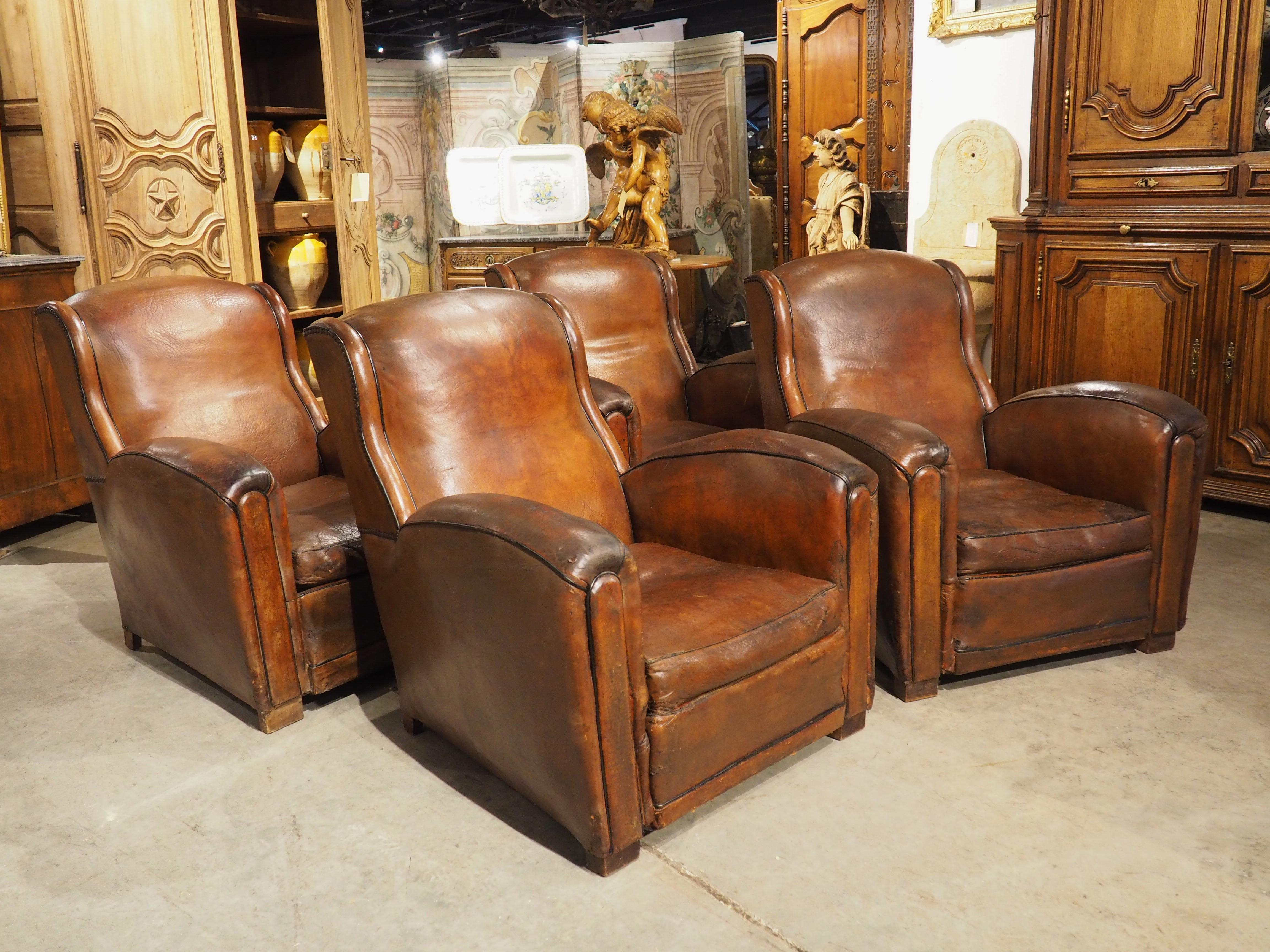 Furniture from the Art Deco period (1910s-early 1930s) was typically crafted using luxurious materials, such as the tanned leather seen on this set of four French club chairs. Hand-crafted around the 1920s, the chairs are perfect examples of Art