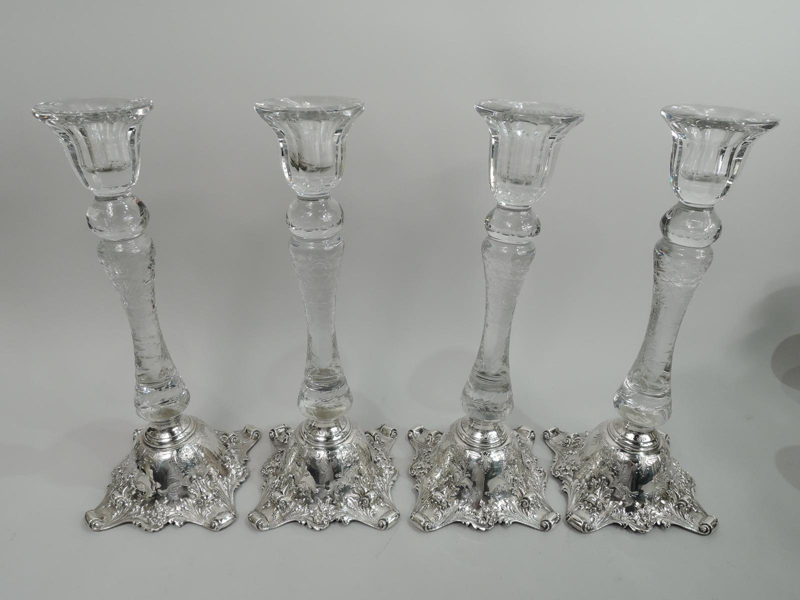 Set of 4 turn-of-the-century Edwardian Classical sterling silver-mounted crystal candlesticks. Made by Graff, Washbourne & Dunn in New York. Each: Knopped and baluster shaft with engraved flowers and leaves surmounted by faceted urn socket. Domed