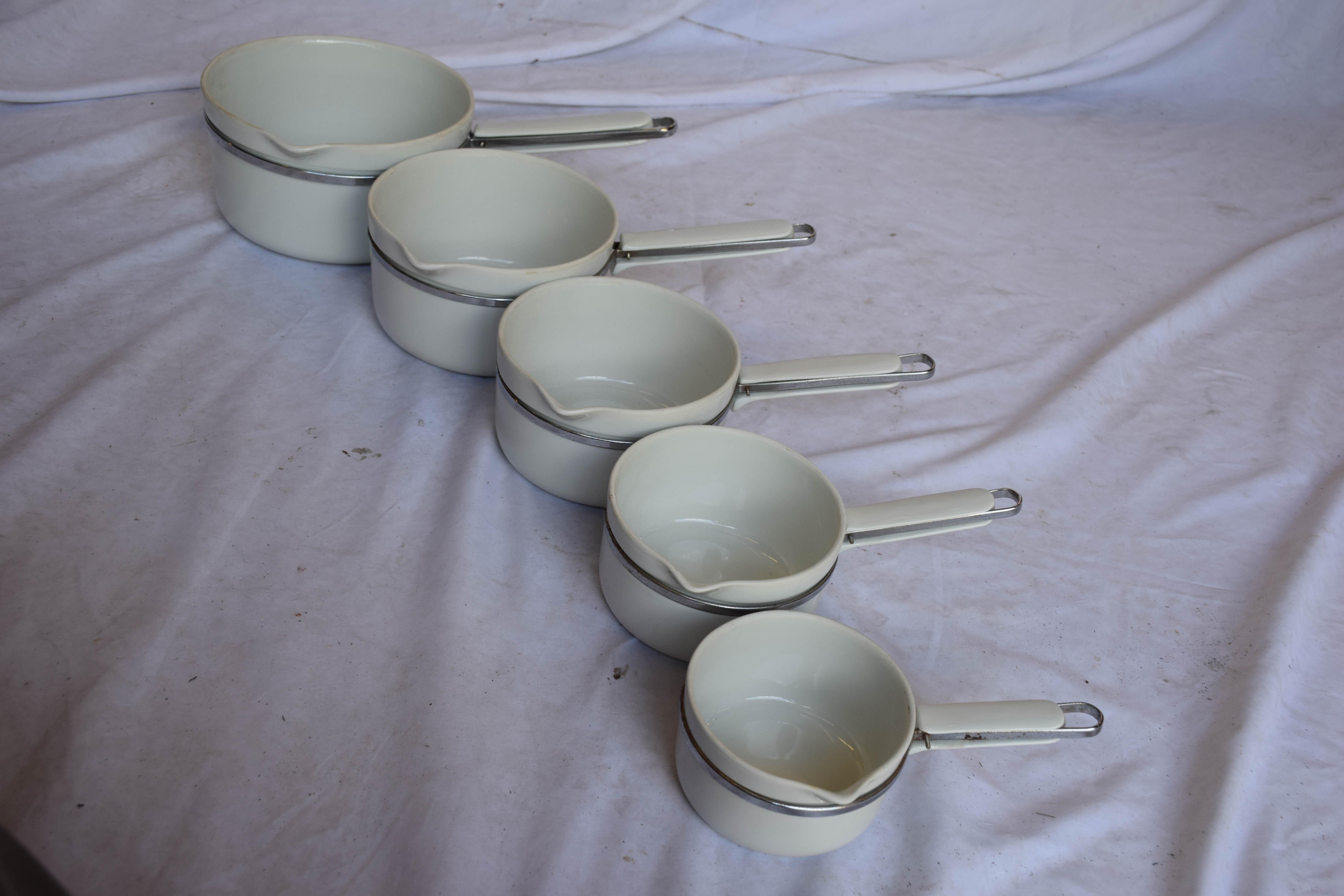 Rare série de 5 pots en aluminite estampillés Frugier Limoges France. Fabriqué en porcelaine et en acier.
Ces 5 casseroles sont en porcelaine ou en aluminite, et peuvent être placées sur le feu. Ils ont également des poignées en porcelaine, ce qui