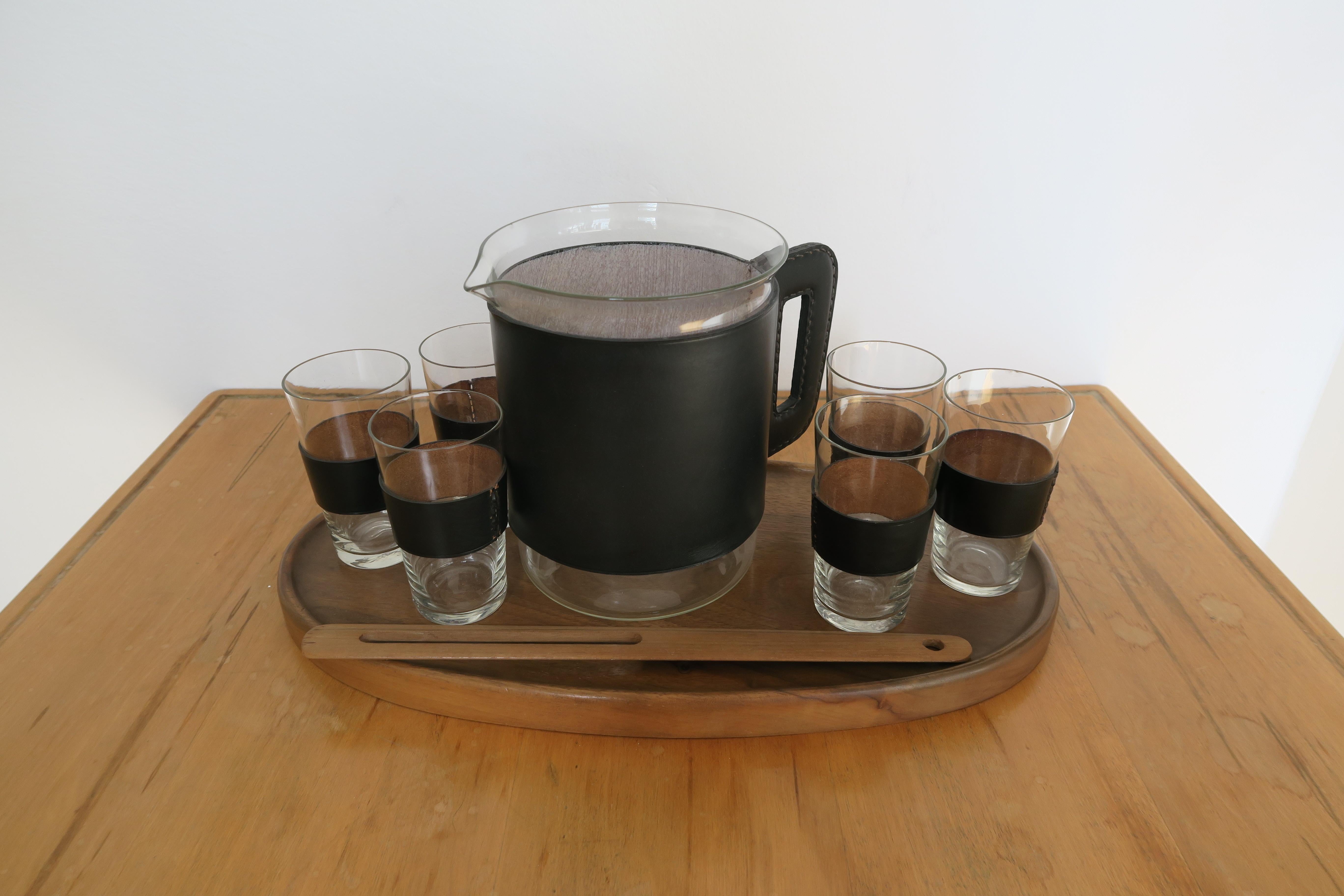 Rare complete serving set of 6 small leather wrapped drinking glasses (hight 9,6cm) and 1 glass pitcher (hight 16cm) featuring leather coverings with intricate stitching. Everything is in great condition (except 2 of the small glasses; see cond.