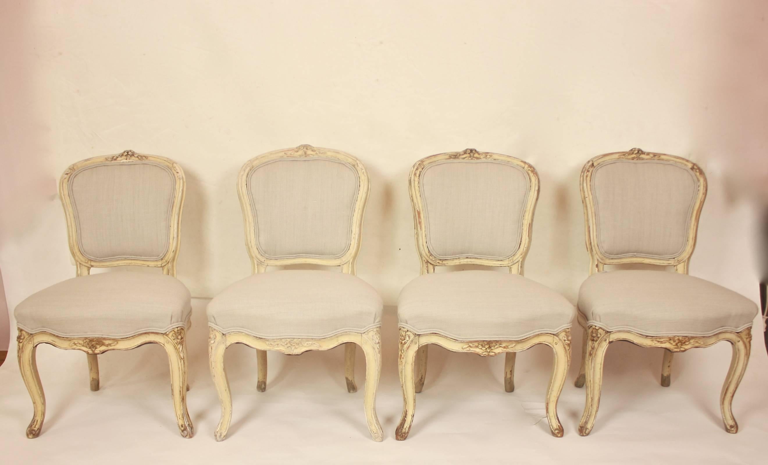 A rare set of eight Louis XV painted and newly upholstered chairs, comprising of four fauteuils and four side chairs. The chairs are painted in a white/ cream colour and covered in silver/ grey linen fabric. Both armchairs and side chairs with a