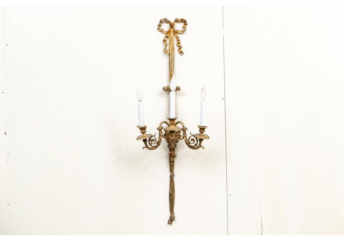 Very fine and rare set of Classic French antique sconces. Tall ribbon forms with bows at the top, open half circles with vines and berries in the center. The three leafy scrolled lights with serrated bobeches. The lower ribbon supports end in